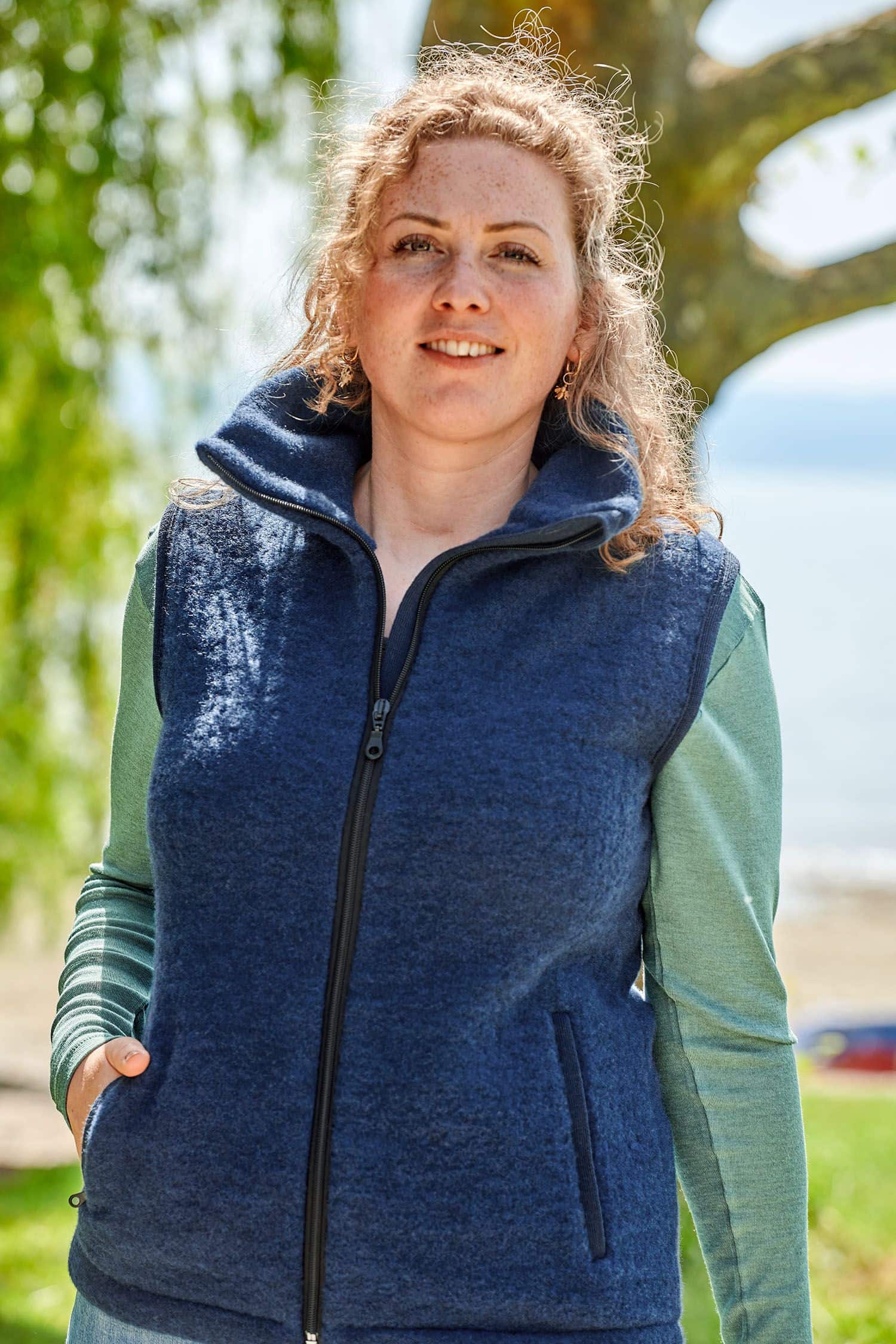 Frau mit grünem Shirt trägt eine blaue ärmellose Weste aus bio Wolle (kbT) vom Finkhof
