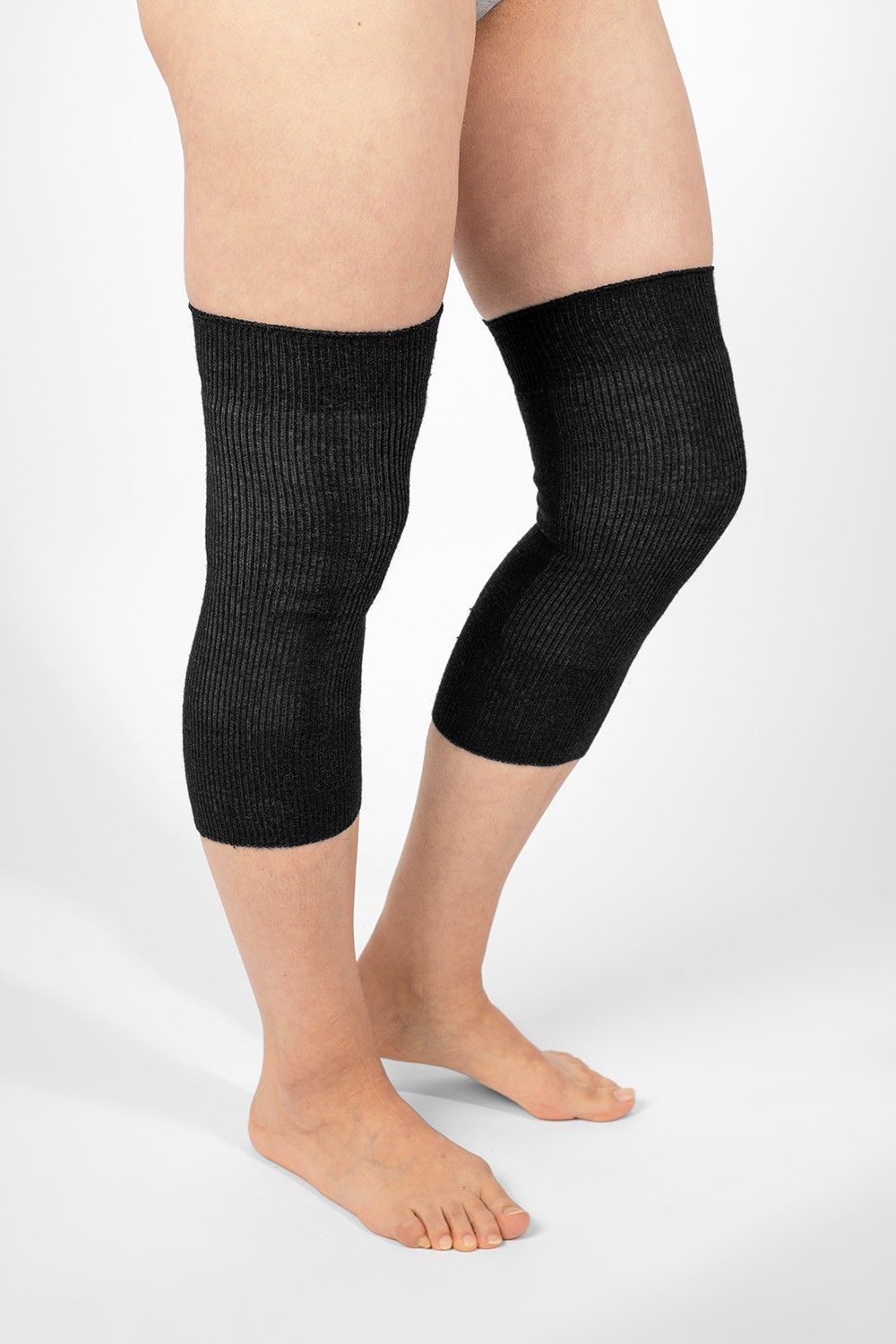 Model trägt schwarze Kniewärmer aus bio Wolle (kbT), Seide, Baumwolle und Elasthan