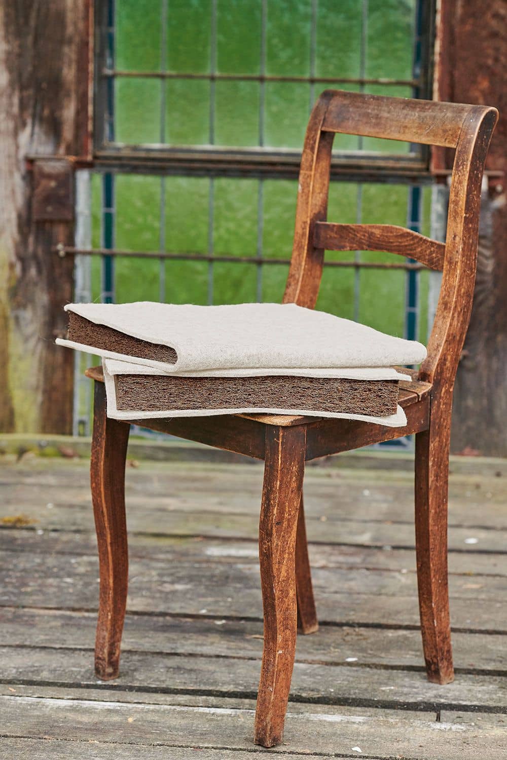 weiße Finkhof Keilkissen aus bio Wolle (kbT) und Kokos auf braunem Holzstuhl