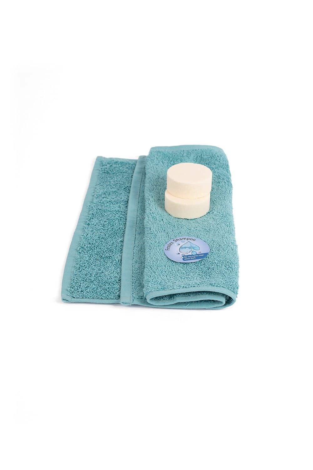 festes Shampoo ohne Duft liegt auf einem türkisen Handtuch