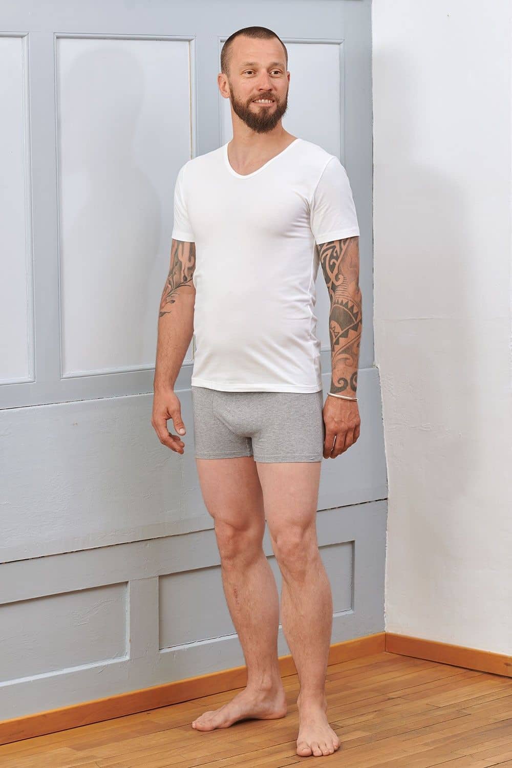 Mann trägt graue Boxershorts und ein weißes Kurzarmshirt aus bio Baumwolle (kbA) und Elasthan mit V Ausschnitt