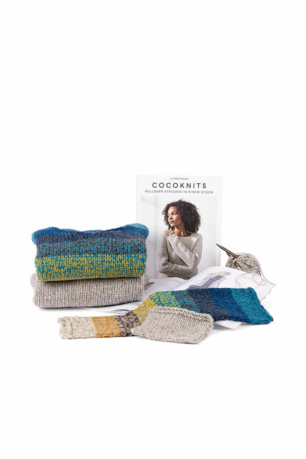 Cocoknits Buch ,,Cocoknits" mit fertigen Pullis im Vordergrund und angefangenem Projekt auf der rechten Seite