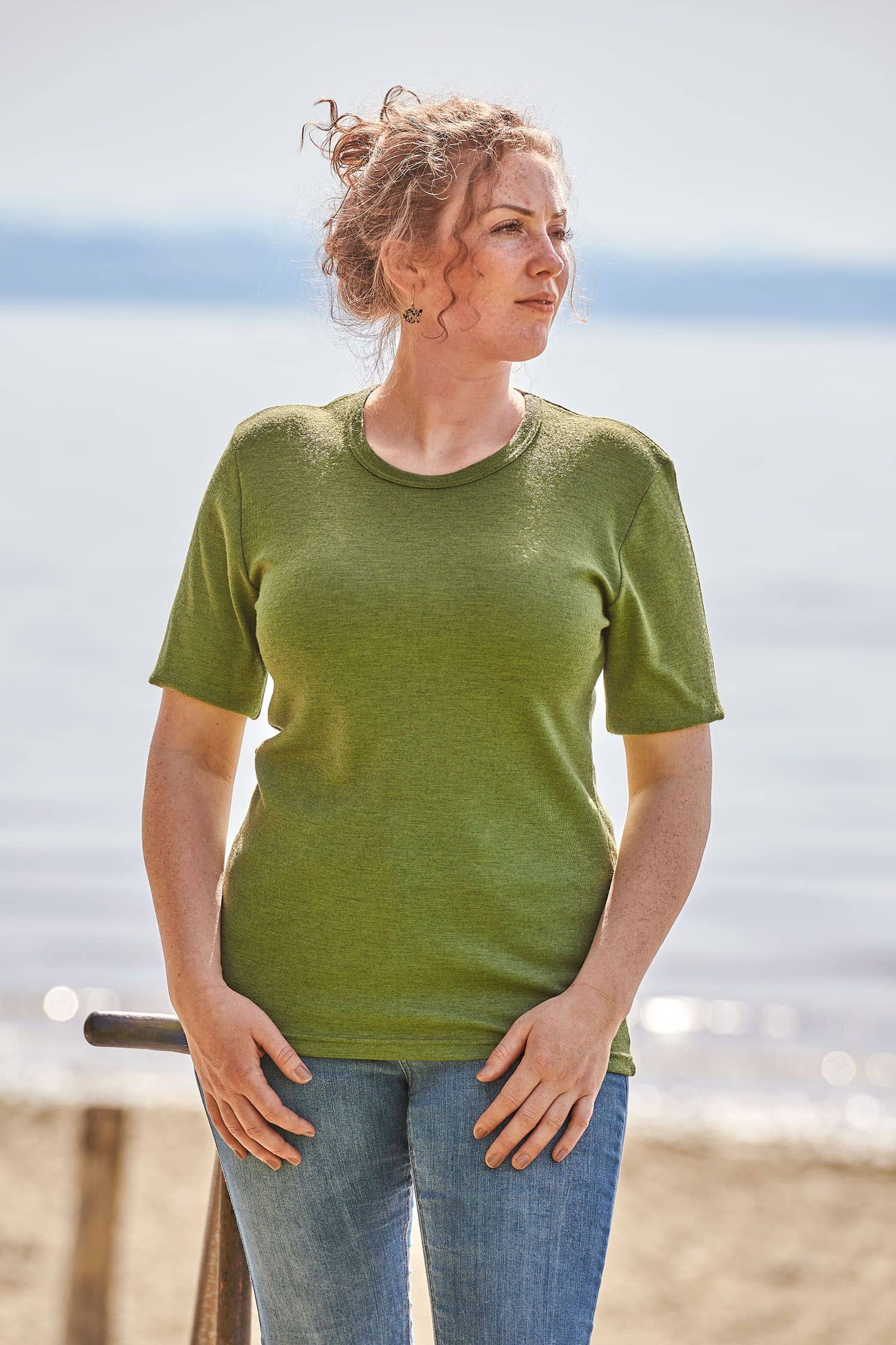 Frau trägt eine Jeans und ein grünes kurzärmeliges Wollhemd aus bio Merinowolle (kbT)