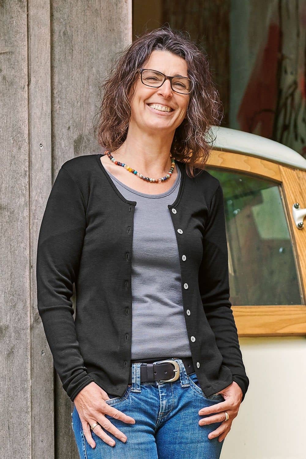 Frau trägt graues Shirt und schwarzer Cardigan mit Knöpfen aus bio Wolle (kbT) und Elasthan