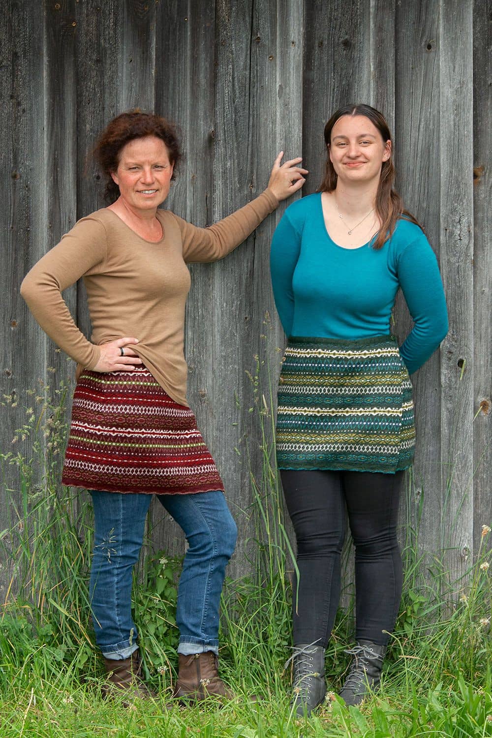 Cacheur Nordic Frauen vor Holzwand tragen rot und blaugemusterten Cacheur aus bio Wolle (kbT) mit türkisem und beigem Shirt dazu Jeans