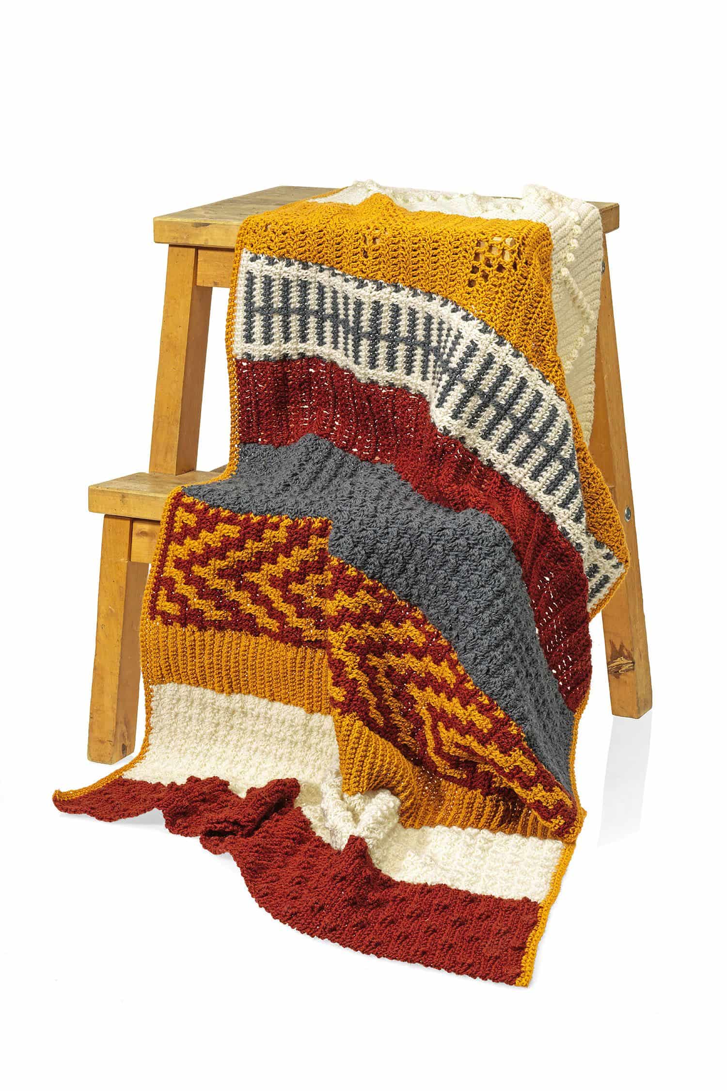 bunte Decke aus dem Buch ,,Mix & Match Farbenfrohe Decken häkeln" über Hocker gelegt