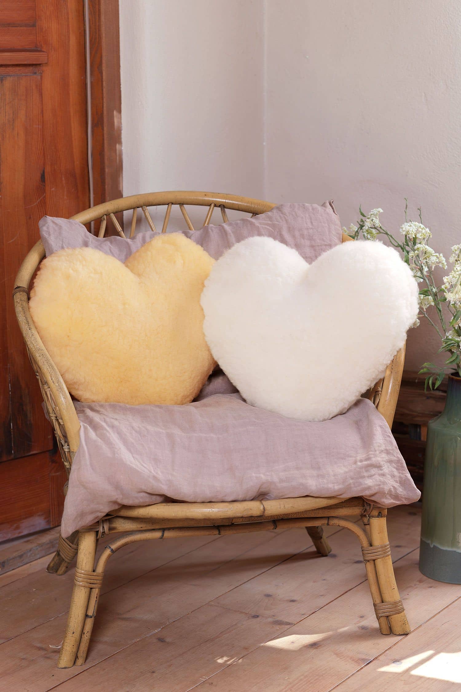 Großes Herz Kissen in Herzform aus Finkhof Schaffell liegen auf einem Korbstuhl