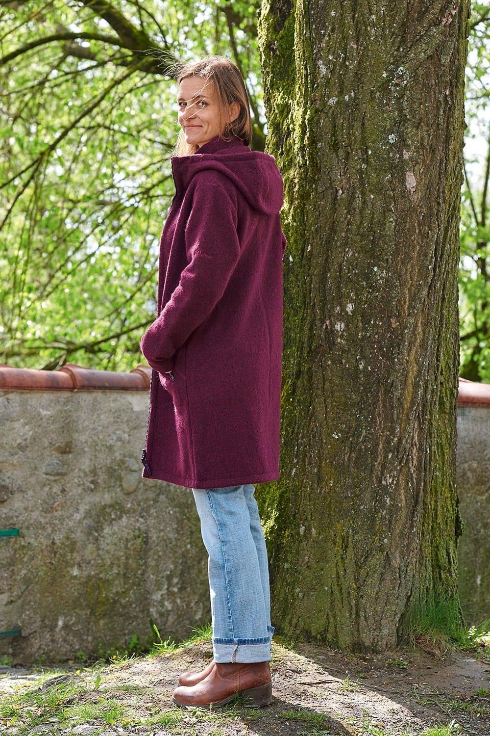 Seitenansicht von Frau mit Jeans und gewalktem Wollmantel in beere