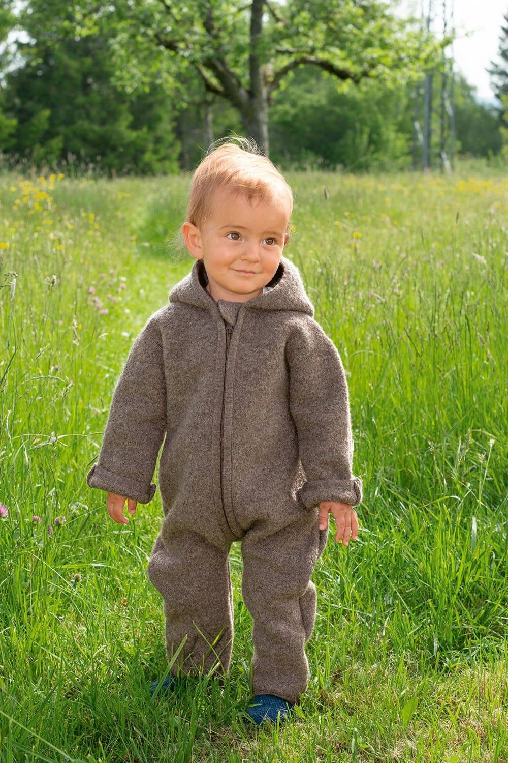 Walkoverall walnuss Gr. 62/68 Kind steht auf einer Wiese und trägt einen walnussbraunen Walkoverall aus bio Wolle (kbT) vom Finkhof