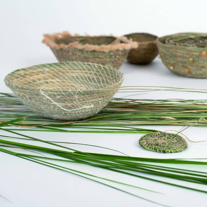 mehrere Graskörbchen mit Grashalmen auf weißem Untergrund