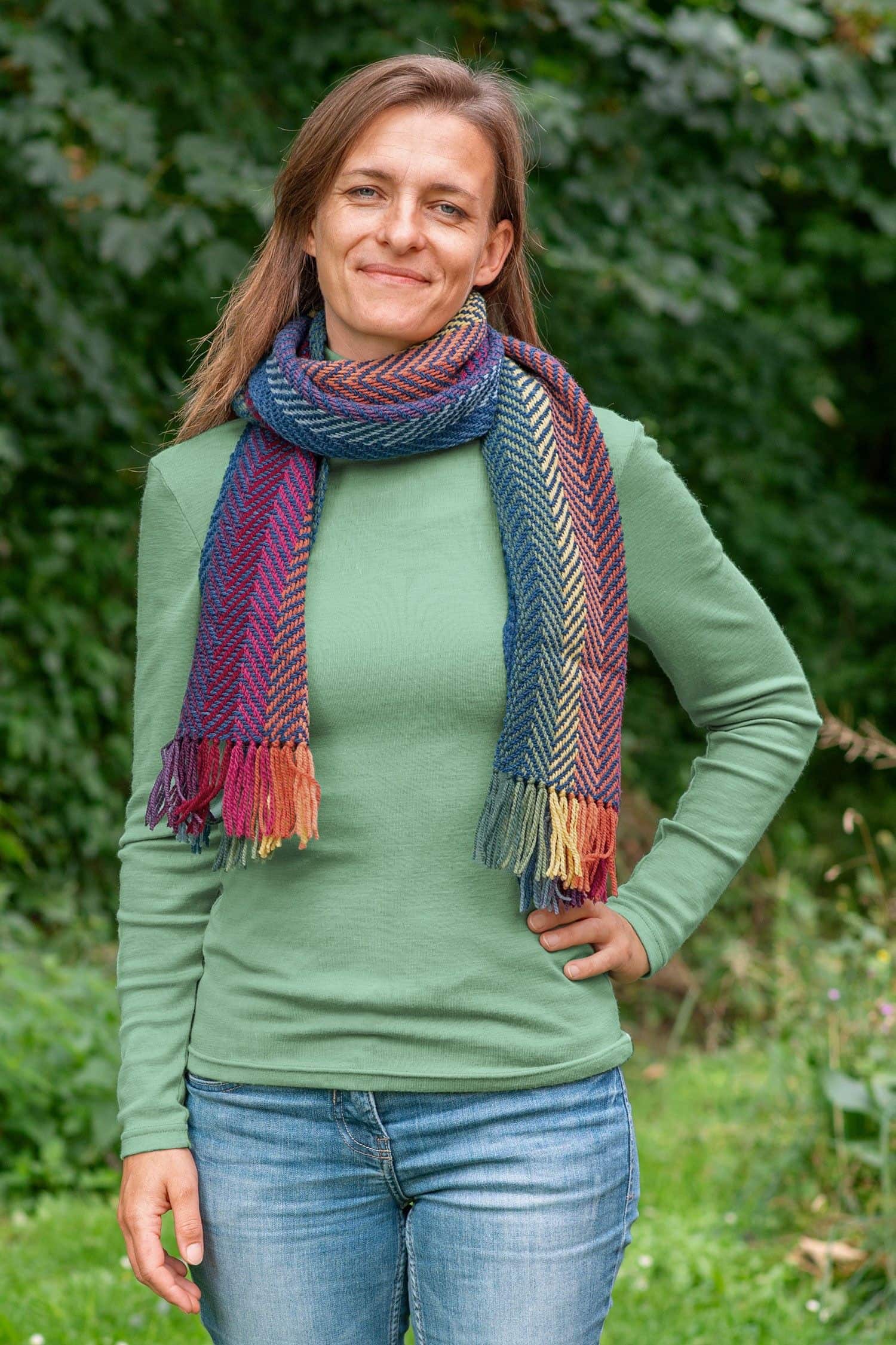 Frau mit schilfgrünem Shirt trägt pflanzengefärbten und handgewebten Wollschal aus bio Wolle (kbT) vom Finkhof