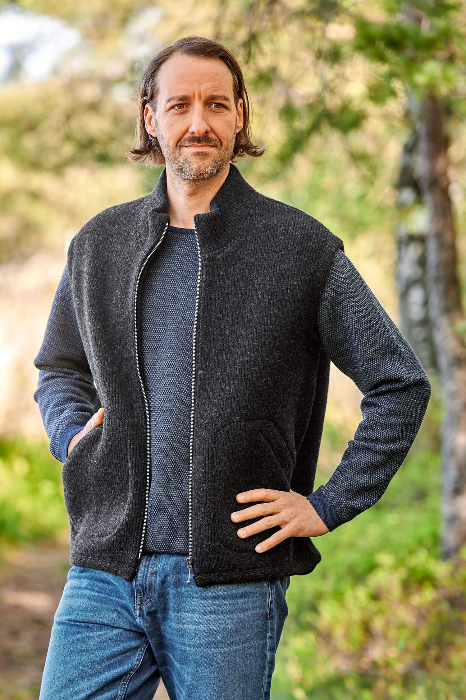 Mann mit grauem Pulli trägt anthrazitfarbene Wollwalkweste aus bio Wolle (kbT) ohne Ärmel vom Finkhof