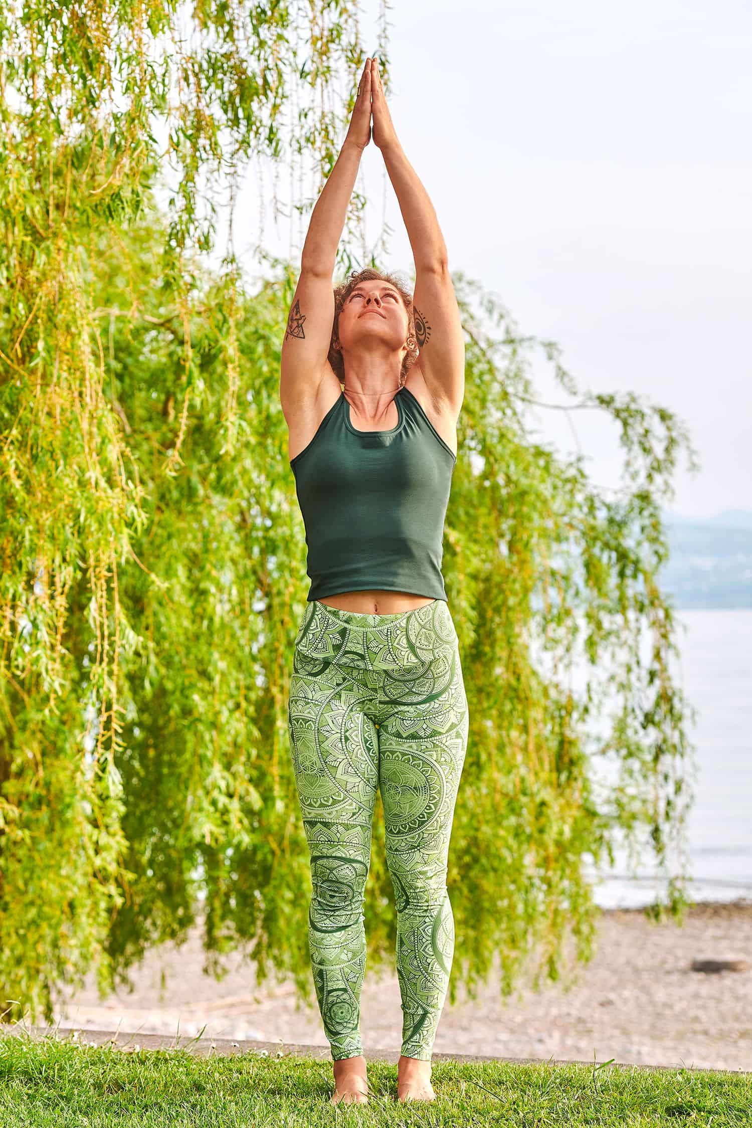Frau in Yogapose trägt eine grün gemusterte Yoga Leggings aus bio Baumwolle (kbA) und Elasthan mit grünem Top