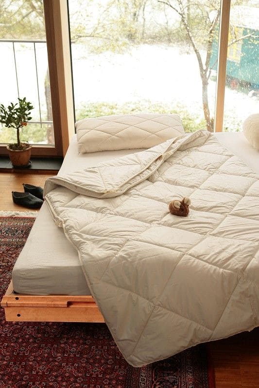 Kombi Steppdecke aus bio Wolle (kbT) und bio Baumwolle (kbA) mit 200x220cm vom Finkhof liegt auf Bett vor großem Fenster