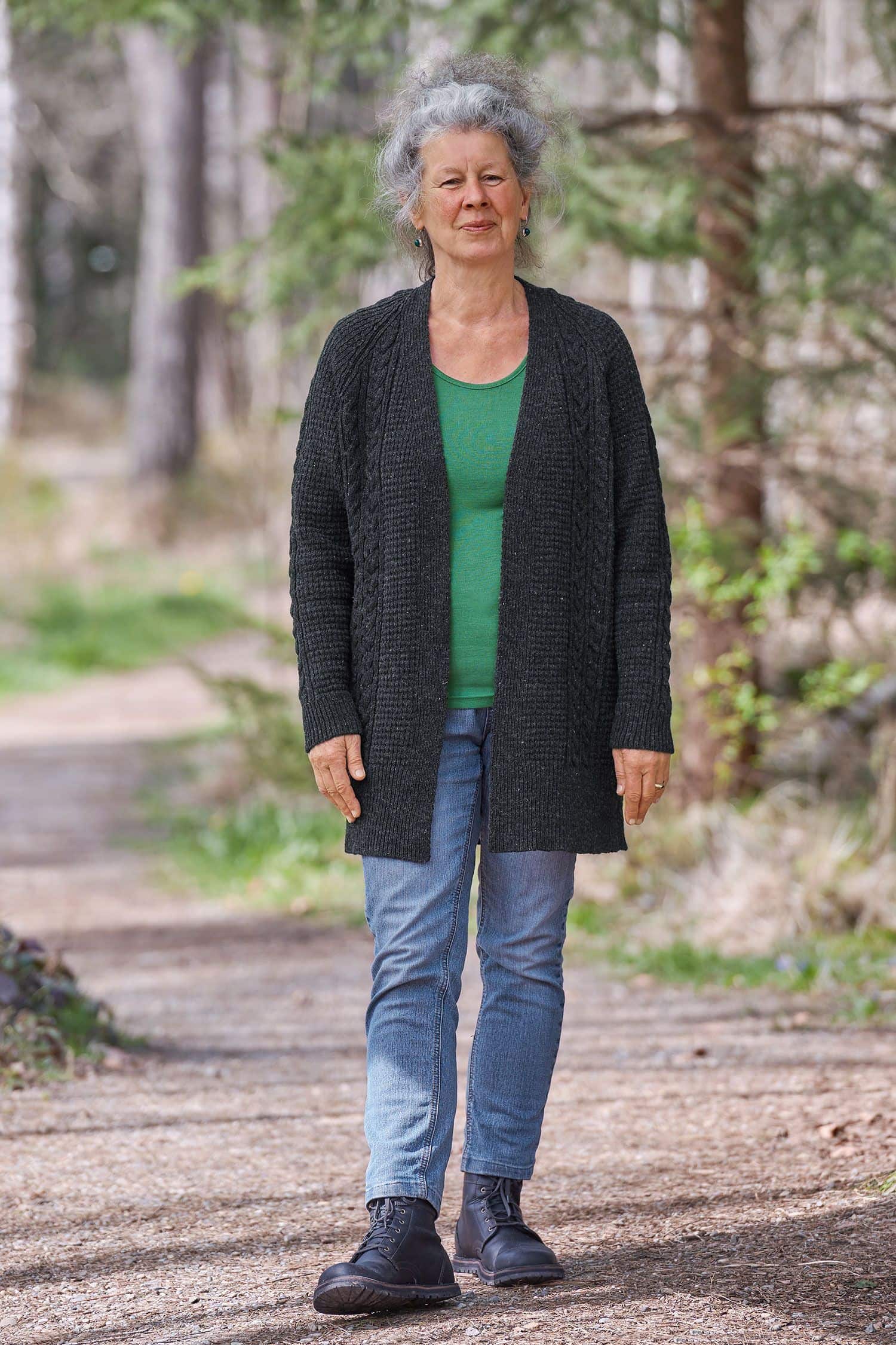 Frau trägt anthrazitfarbenen Cardigan vom Finkhof mit Zopfmuster aus bio Wolle (kbT) , grünes Shirt und Jeans