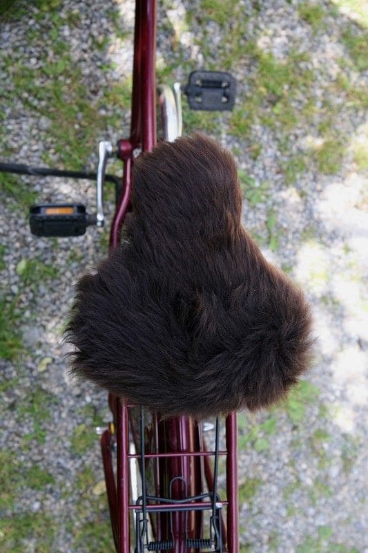 brauner breiter pflanzlich gegerbter Sattelbezug vom Finkhof aus bio Wolle (kbT) und Schaffell auf rotem Fahrrad von oben