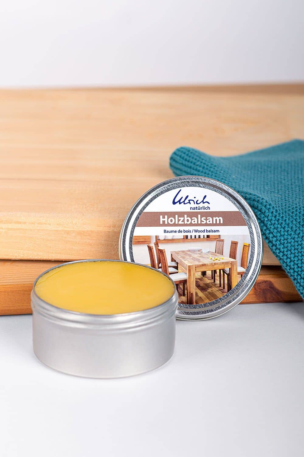 Holzbalsam 150 ml Holzbalsam aus Leinöl und Bienenwachs in silberner offener Aludose mit 150 ml, Holz und türkiser Lappen im Hintergrund