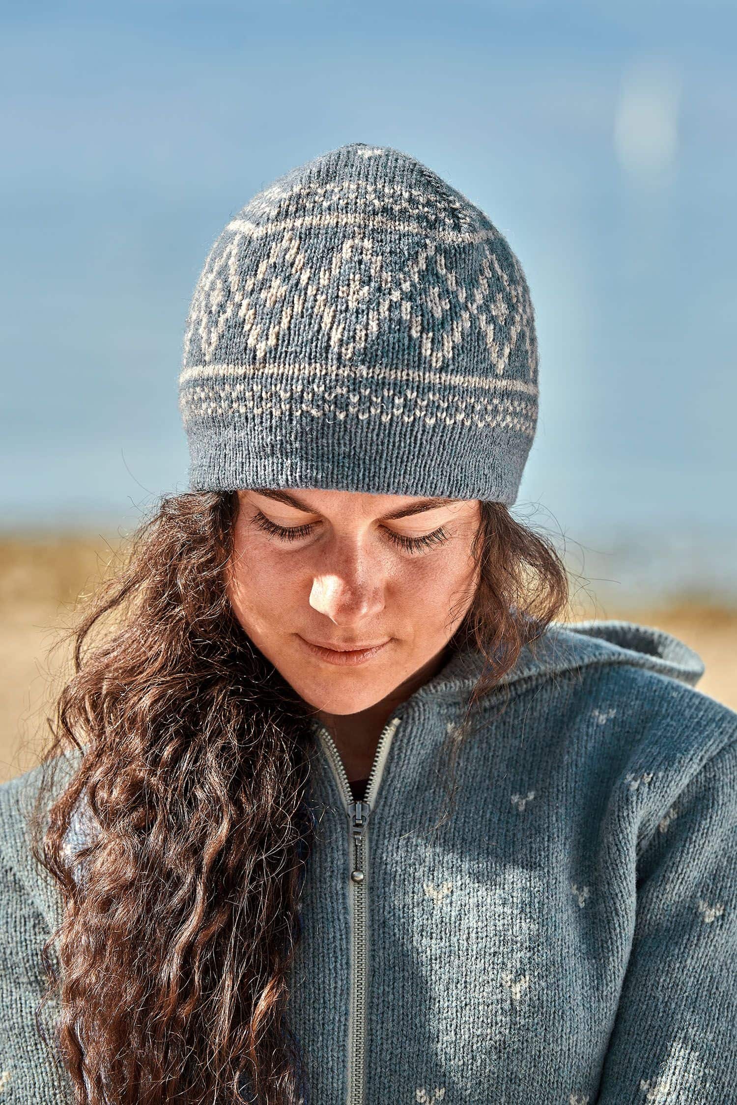 Frau trägt rauchblaue Mütze mit Norwegermuster aus bio Wolle (kbT) vom Finkhof und eine blaue Jacke