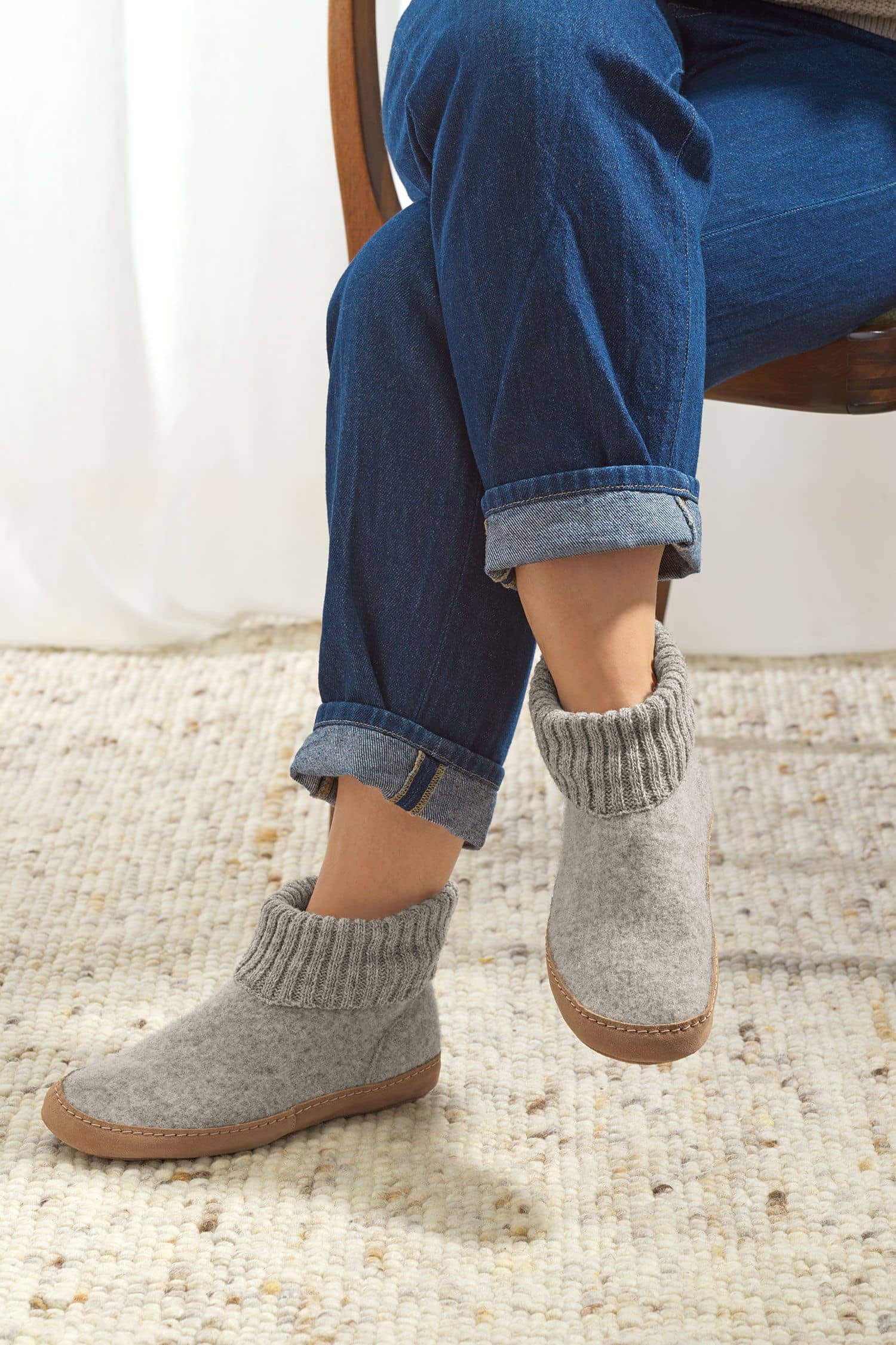 Person trägt hellgraue Finkhof Hüttenschuhe aus bio Wolle (kbT) mit einer Sohle aus pflanzlich gegerbtem Rindsleder