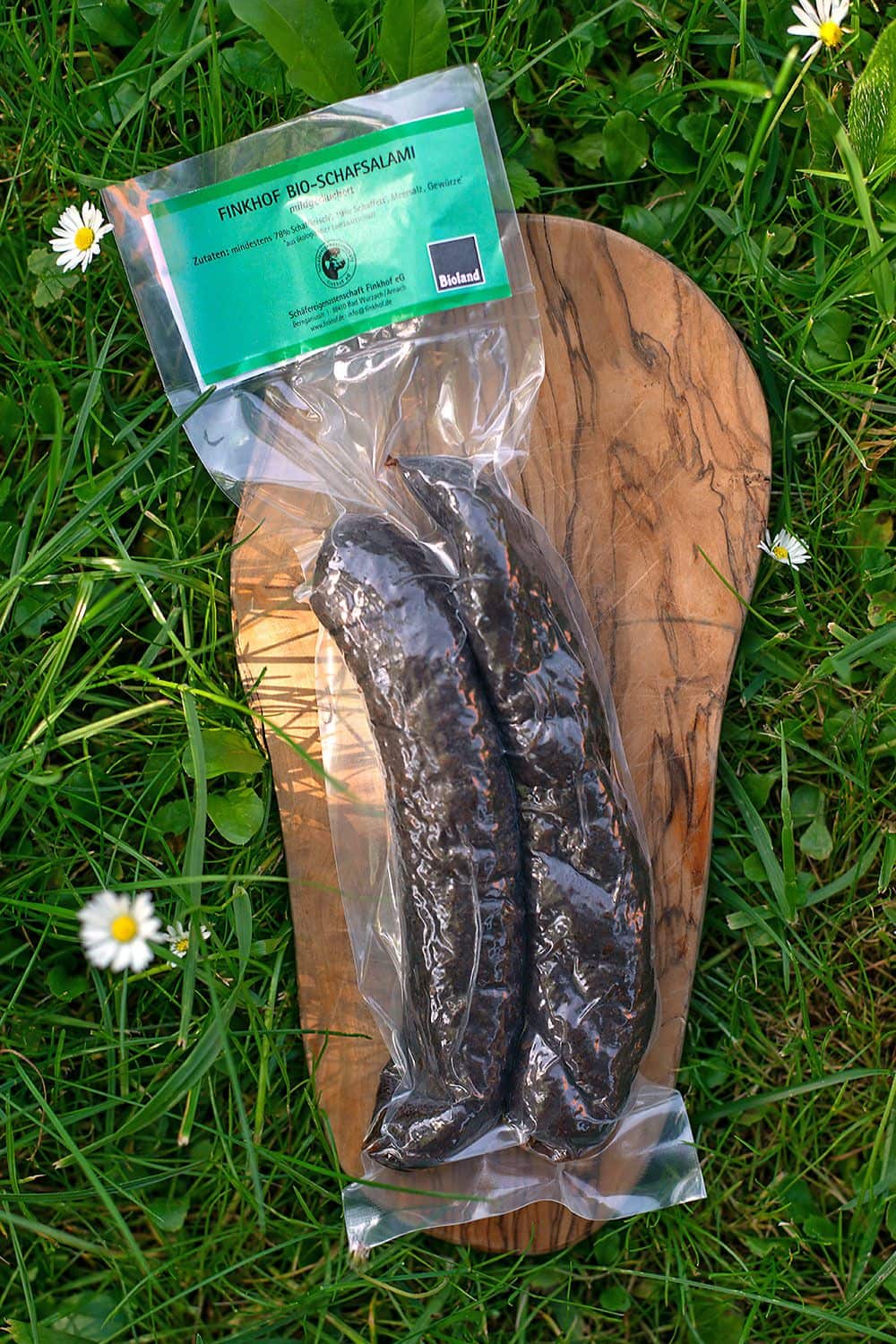 verpackte bio Schafsalami vom Finkhof auf einem Brettchen auf der Wiese
