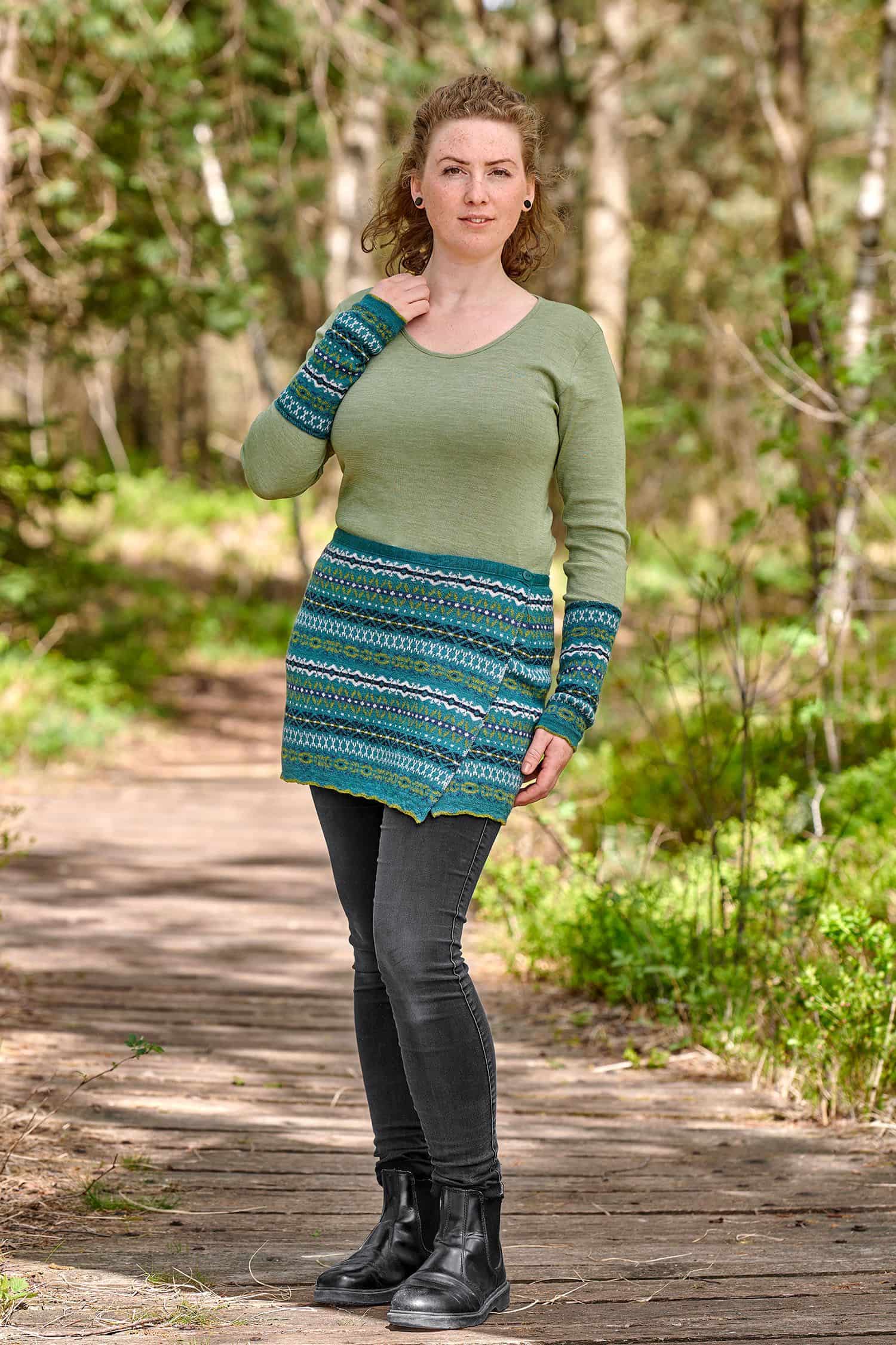 Frau trägt einen türkisen Cacheur mit nordischem Muster aus bio Wolle (kbT), passende Armstulpen und ein grünes Shirt