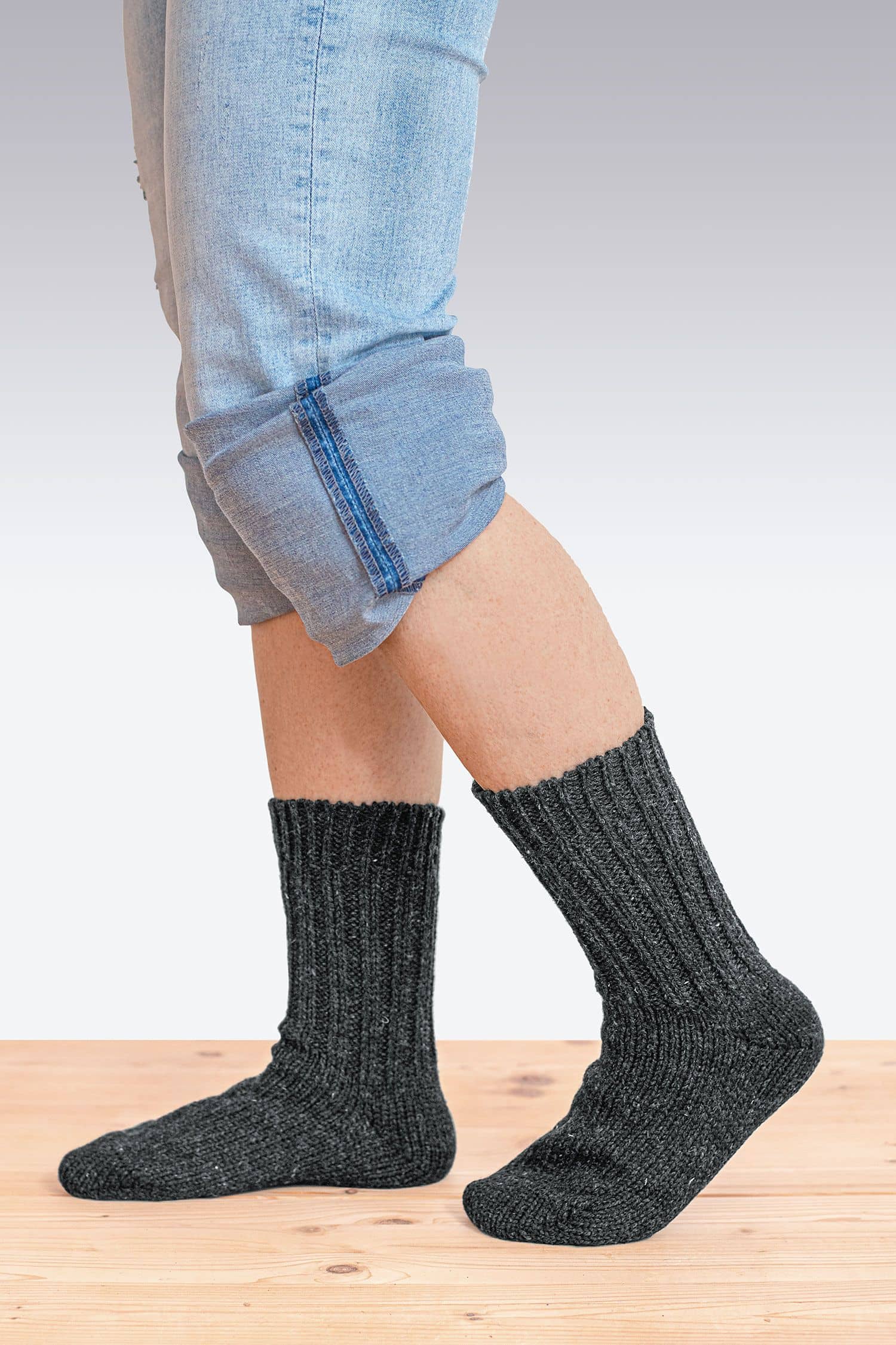 Person mit gekrempelter Jeans trägt dicke anthrazitfarbene Finkhof Socken aus bio Wolle (kbT) von der Seite
