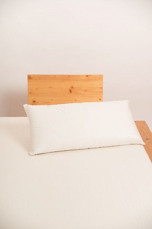 weißes Kopfkissen in 40x80cm aus bio Wolle (kbT) und bio Baumwolle (kbA) vom Finkhof auf hellbraunem Bett