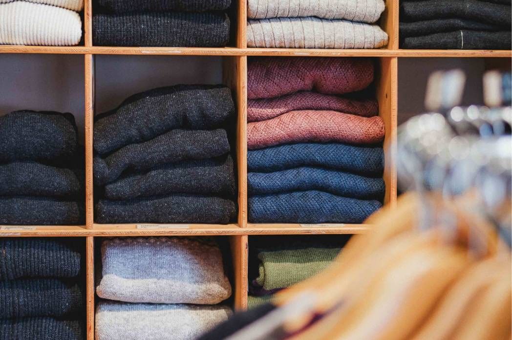 Verschiedenfarbige Wollkleidung im Regal im Finkhof Hofladen