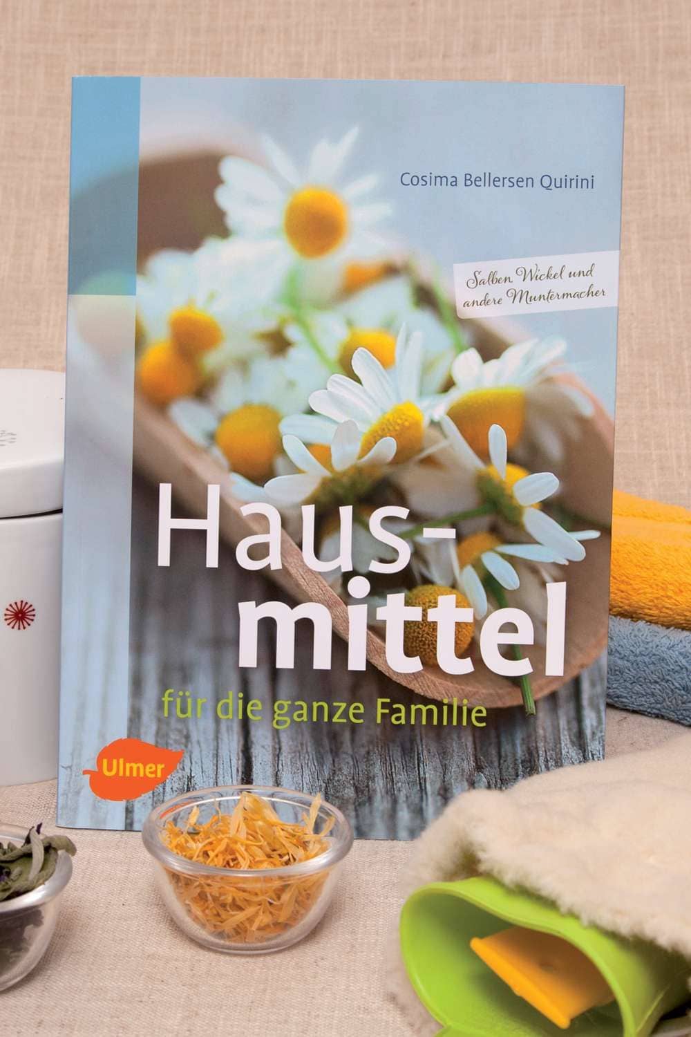 Hausmittel für die ganze Familie Buch ,,Hausmittel für die ganze Familie" als Stimmungsbild mit Wärmflasche und Glasschälchen
