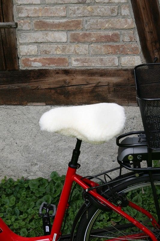 Fahrradsattelbezug pflanzlich gegerbt naturweiß breit schmaler weißer pflanzlich gegerbter Sattelbezug vom Finkhof aus bio Wolle (kbT) und Schaffell auf rotem Fahrrad