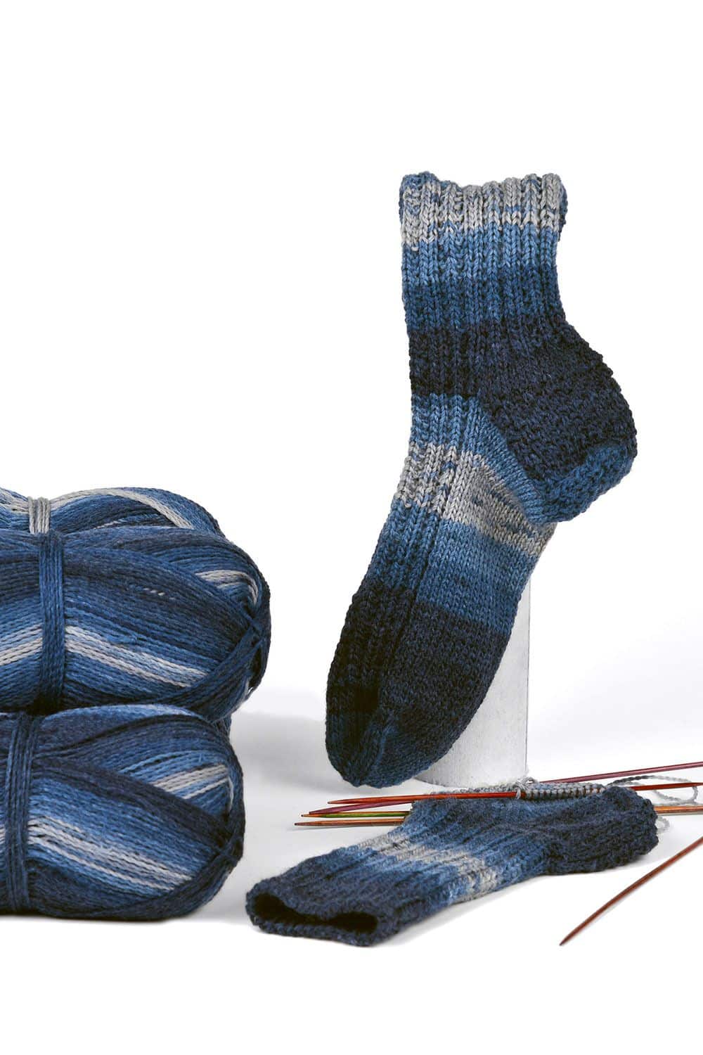 feine blaumelierte Finkhof Sockenwolle aus bio Wolle (kbT) mit Knäulen, fertiger Socke und Stricknadeln