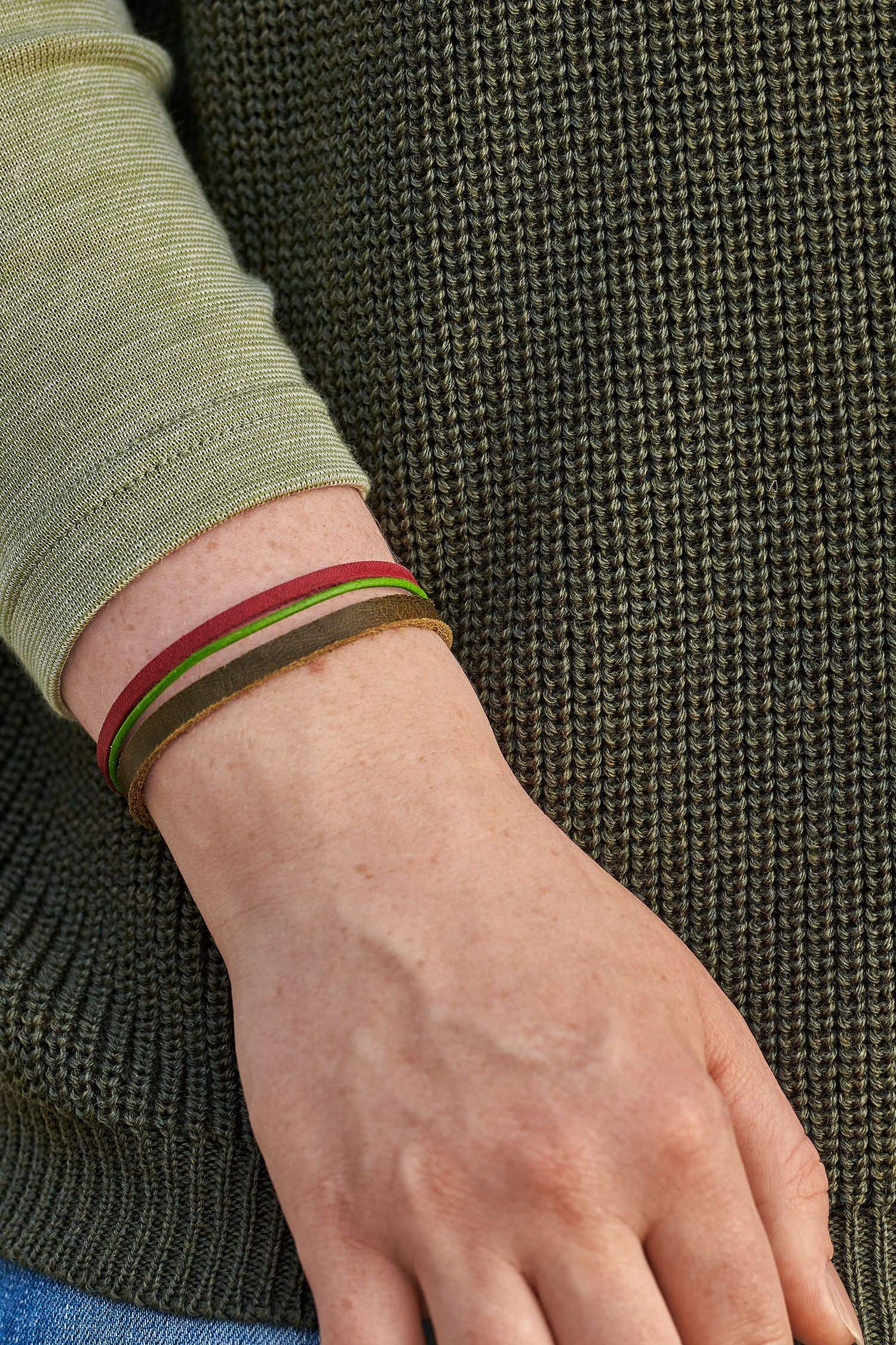 Frau mit grünem Pulli trägt ein Lederarmband olive aus Rinds- und Ziegenleder in rot, braun, grün