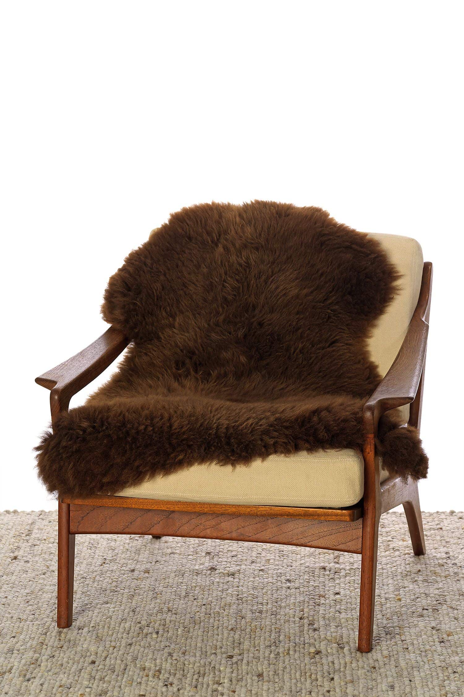 braunes pflanzlich gegerbtes Finkhof Schaffell auf einem Holzstuhl 