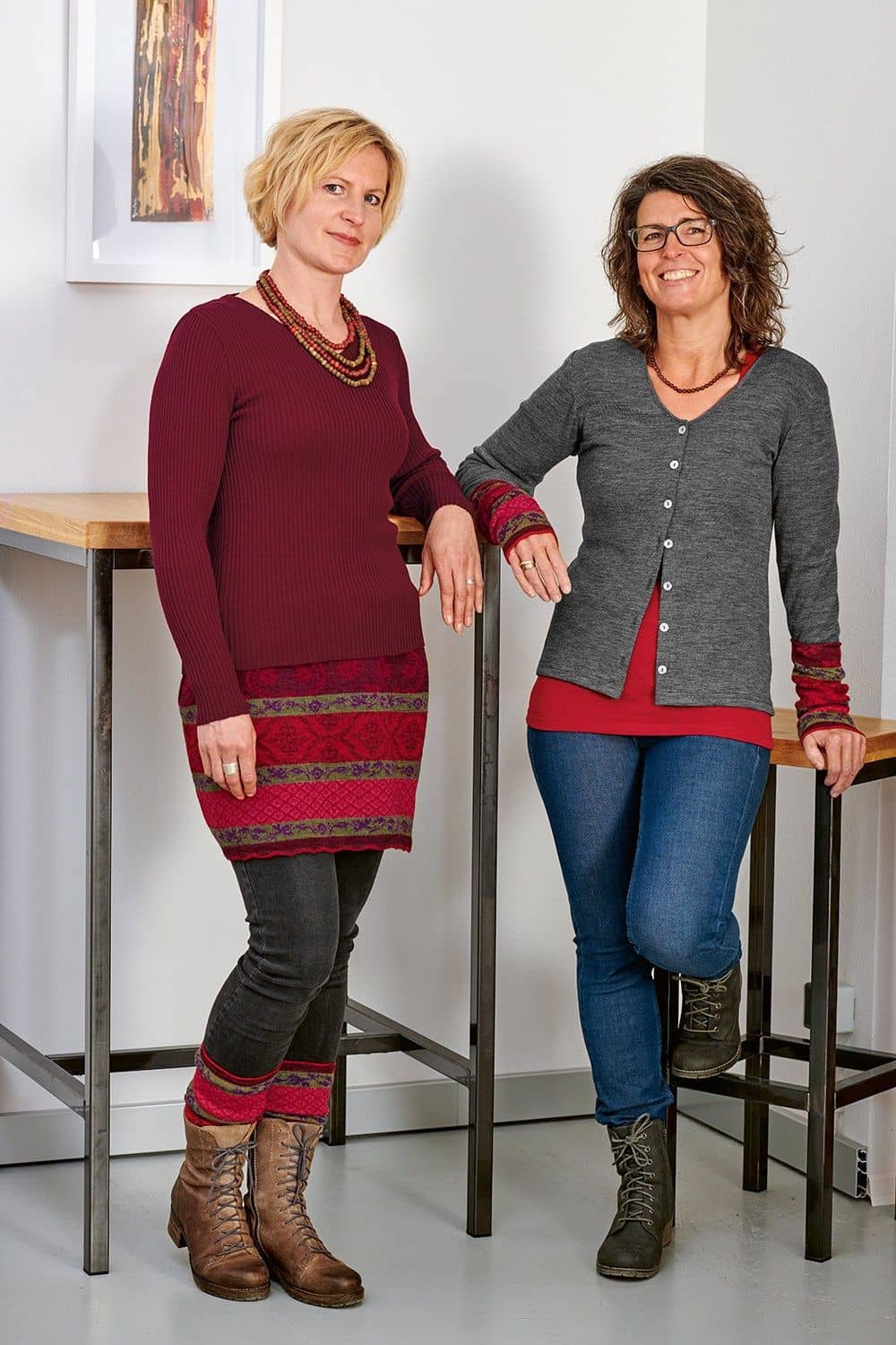 Frauen tragen rotes Shirt, grauer Cardigan, rot gemusterter Cacheur und Stulpen aus bio Wolle (kbT)