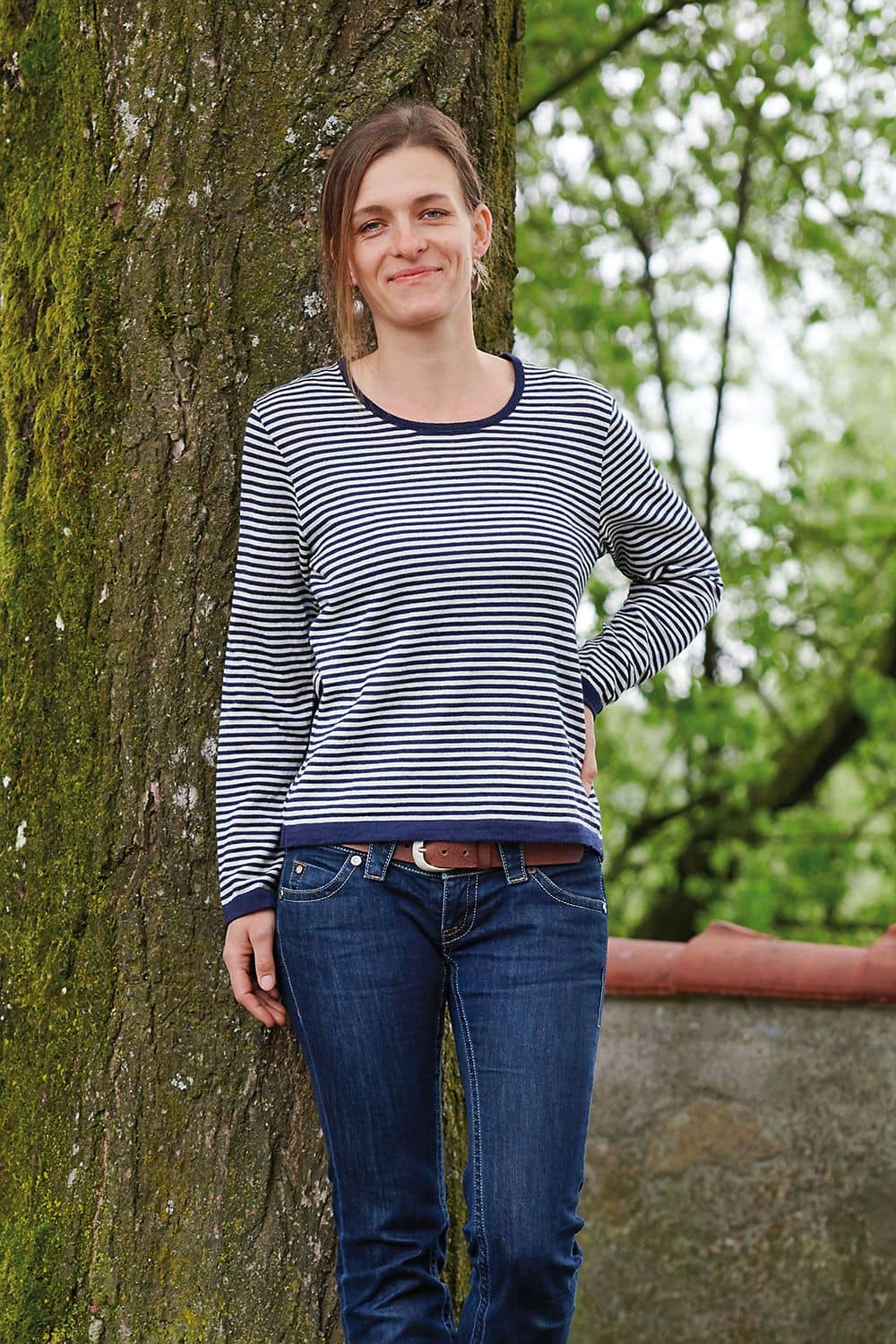 Frau steht vor Baum und trägt ein blau weiß gestreiftes Wollshirt aus bio Wolle (kbT) vom Finkhof