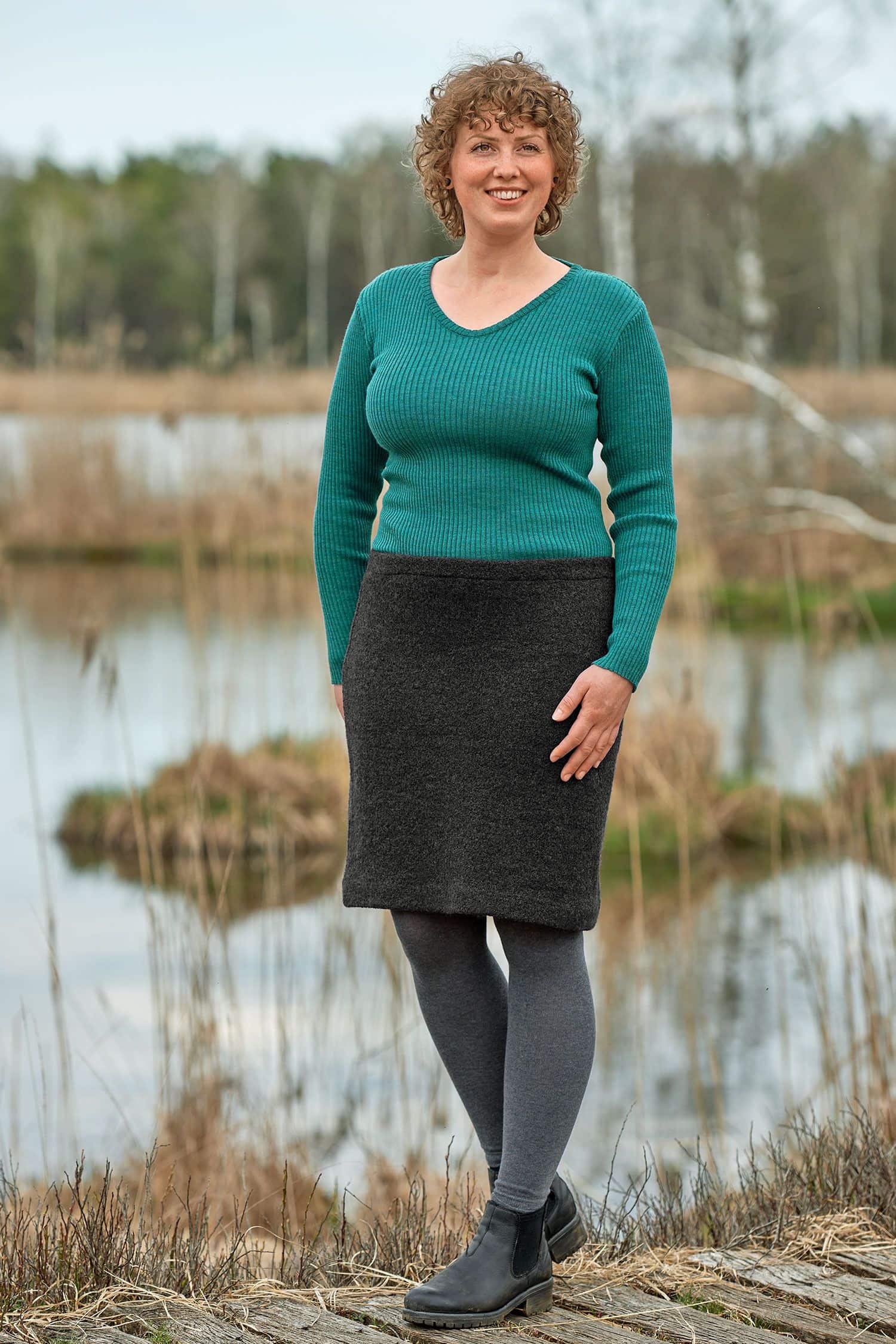 Frau mit tükisem Rippshirt trägt einen anthrazitgrauen Wollkrepprock aus bio Wolle (kbT)