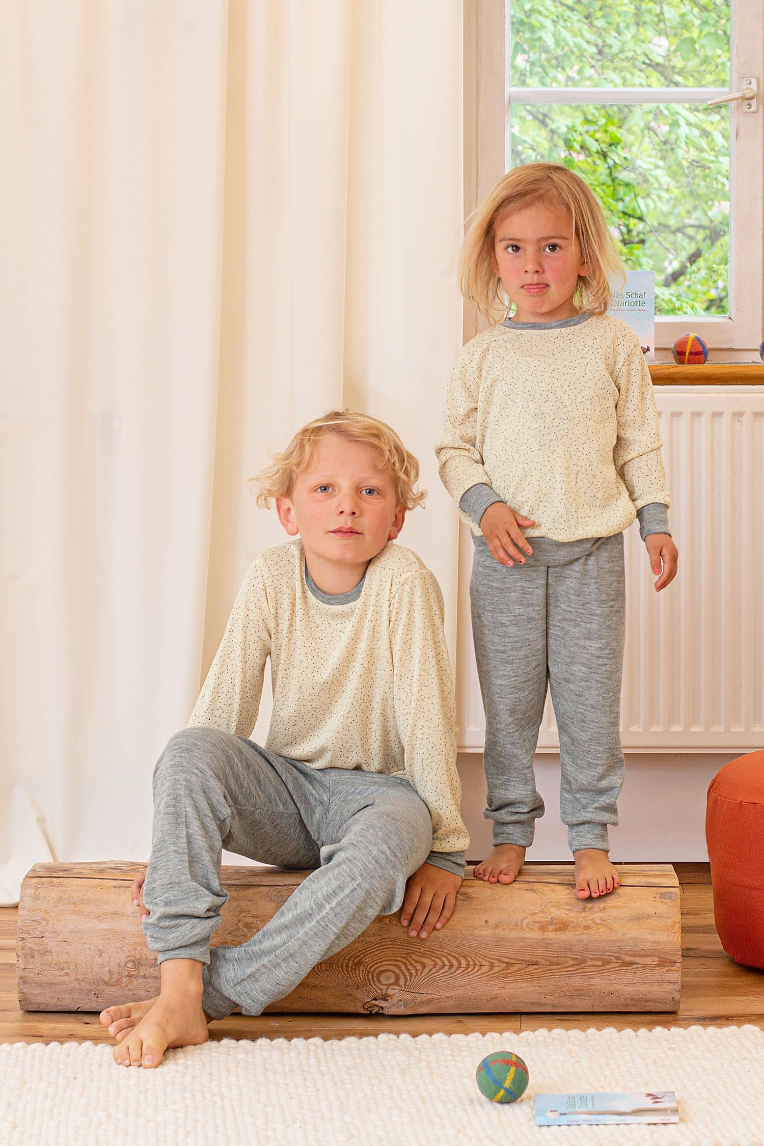 Wolle-Seide Kinder-Schlafanzugoberteil Kinder sitzen auf Balken und tragen Schlafanzughose und Oberteil mit Punkten aus bio Wolle (kbT) und Seide