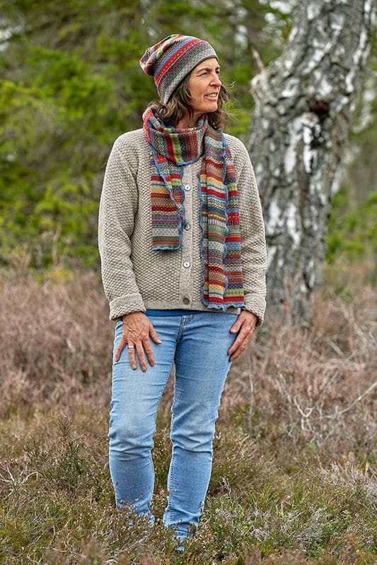 bunt gemusterte Mütze Oslo mit passendem Schal von Frau mit grauer Strickweste und Jeans getragen