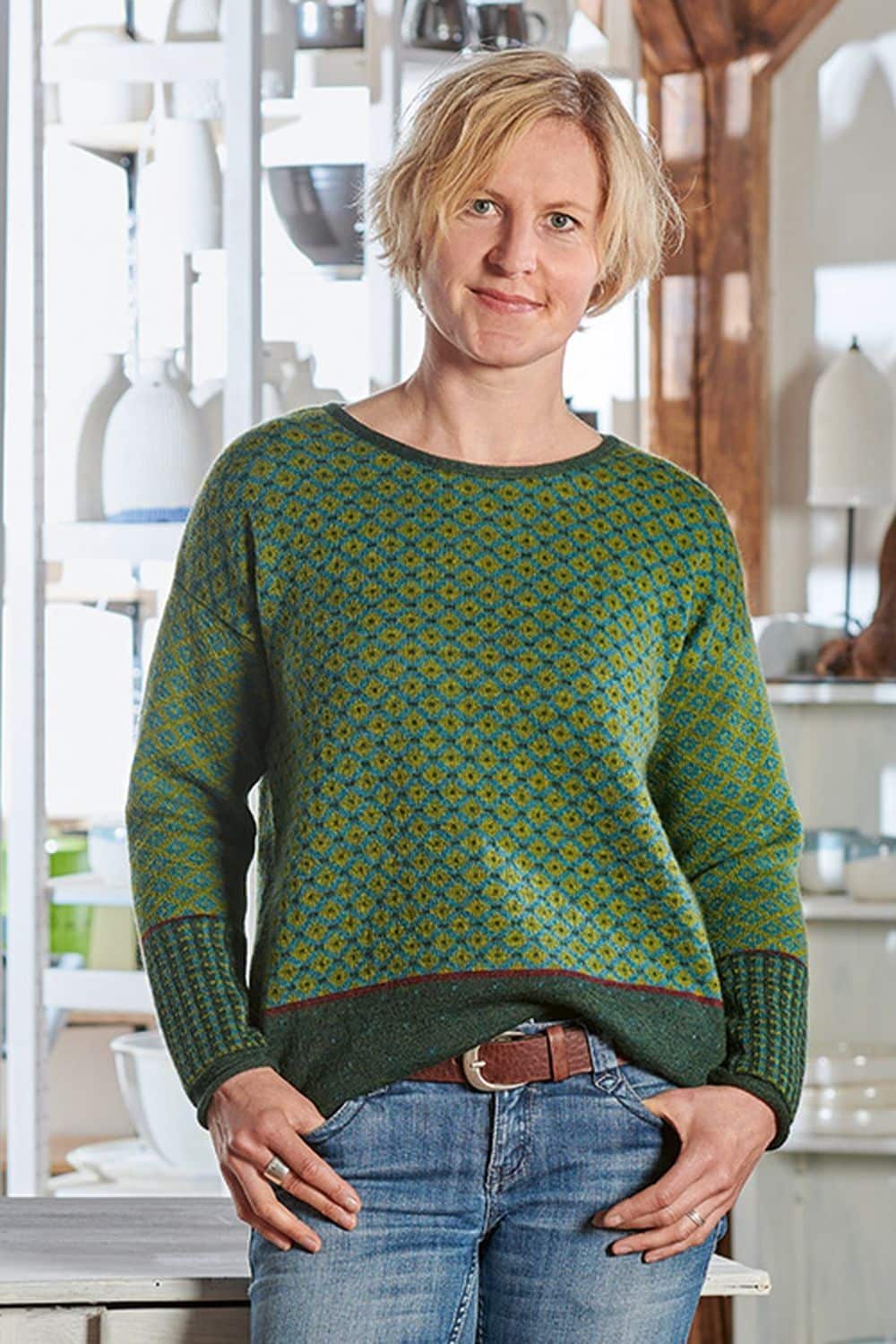 Frau mit Jeans trägt grün türkis gemusterten Pullover aus bio Wolle (kbT)