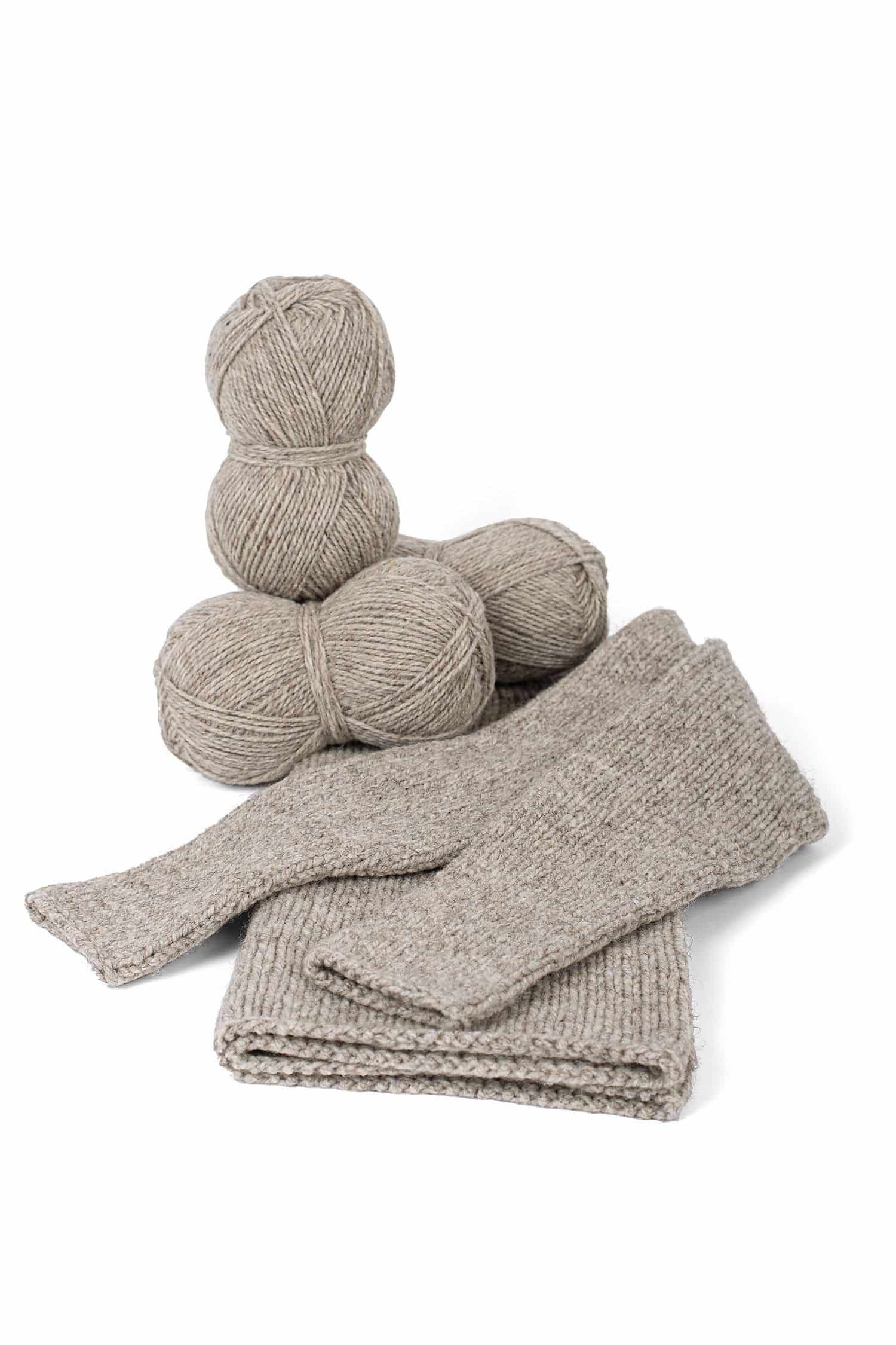 dicke ungefärbte Merinowolle vom Finkhof aus bio Wolle (kbT) in hellgrau mit Knäulen und Strickprojekten, auf weiß