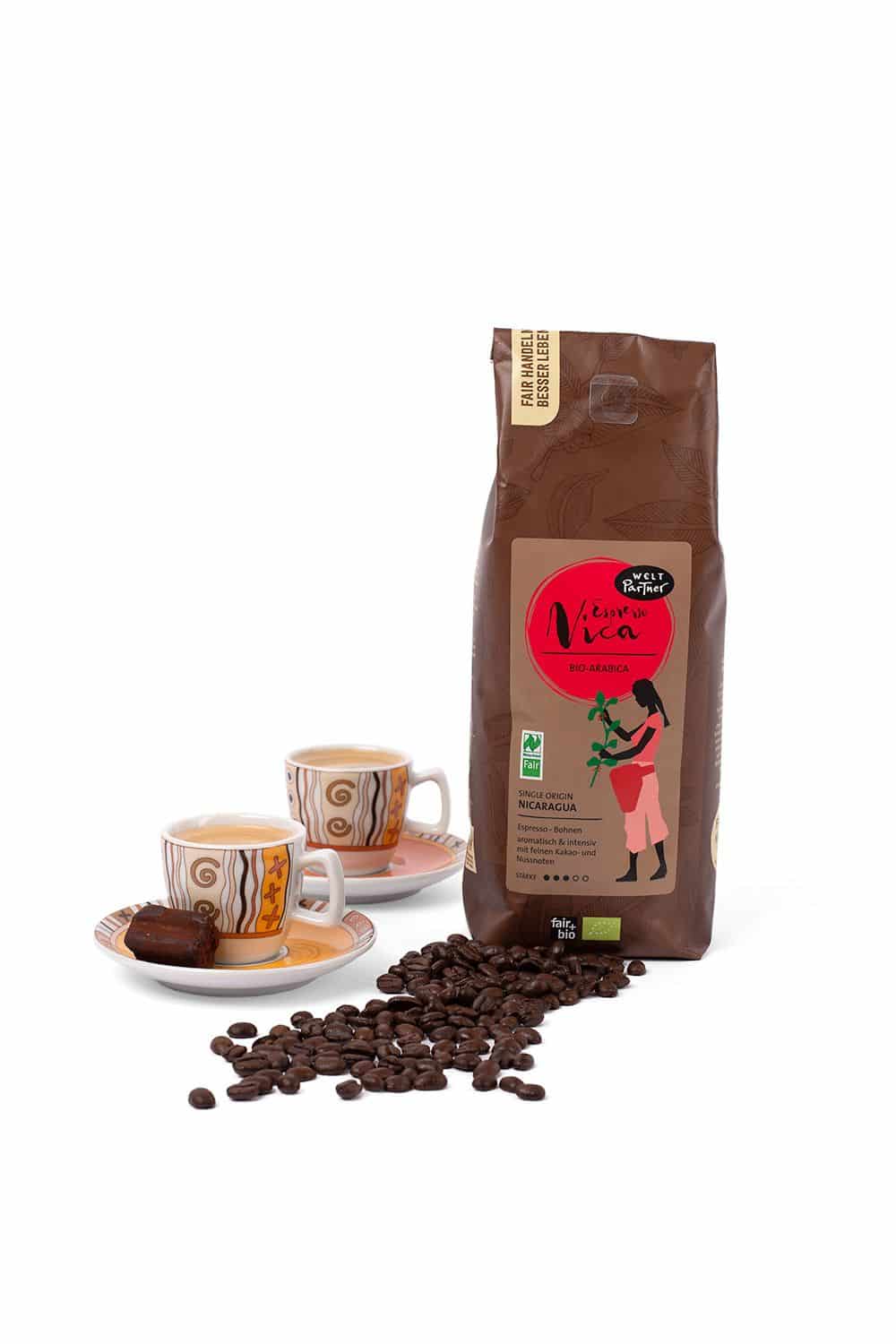 Espresso Nica ganze Bohne 500 g Espresso Nica von WeltPartner mit ganzen Bohnen auf dem Bild in brauner 500g Packung und zwei Kaffeetassen auf der Seite