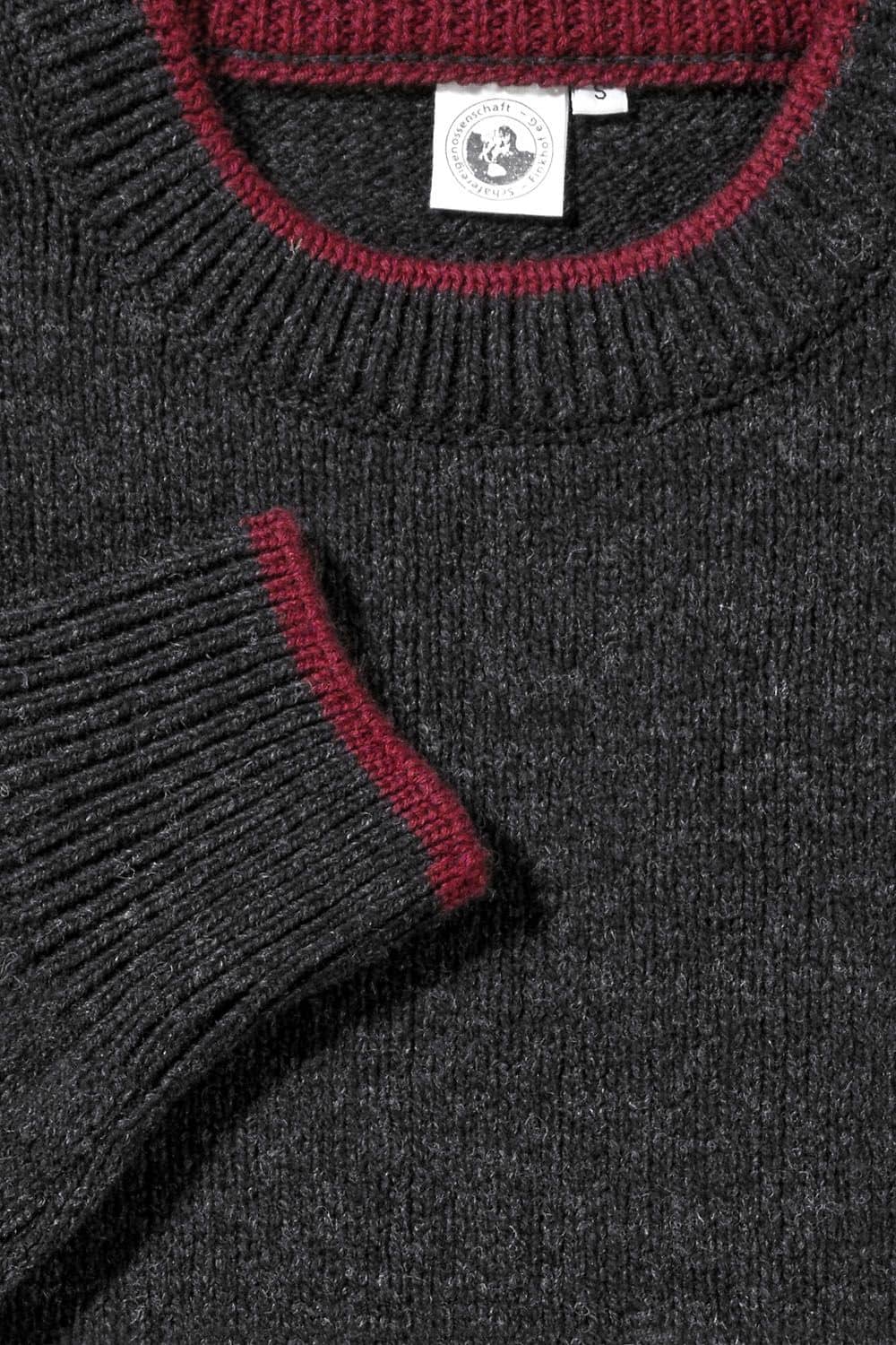 Detailaufnahme der weinroten Kanten des anthrazitgrauen Finkhof Pullis aus bio Wolle (kbT)