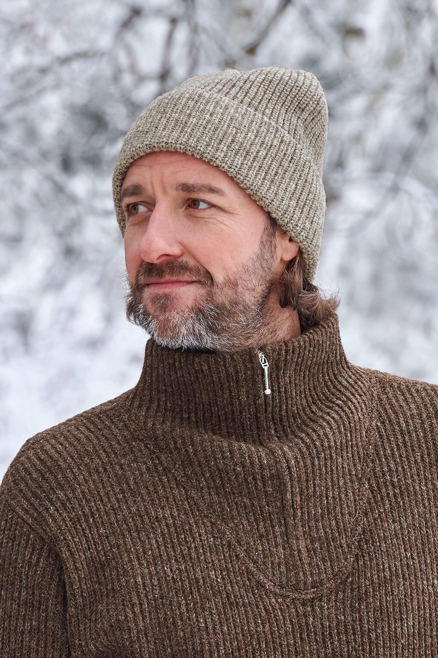 Mann trägt graue Finkhof Mütze aus bio Wolle (kbT) und braunen Finkhof Troyer