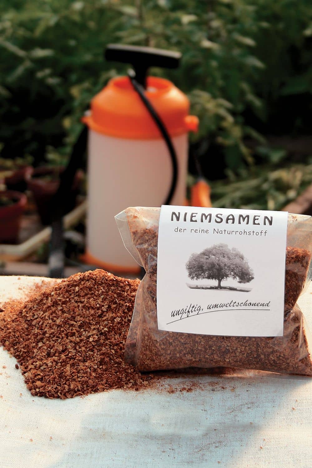 Niemsamen 250g Packung Niemsamen vom Finkhof neben kleinem Häufchen aus Samen mit Zerstäuber im Hintergrund