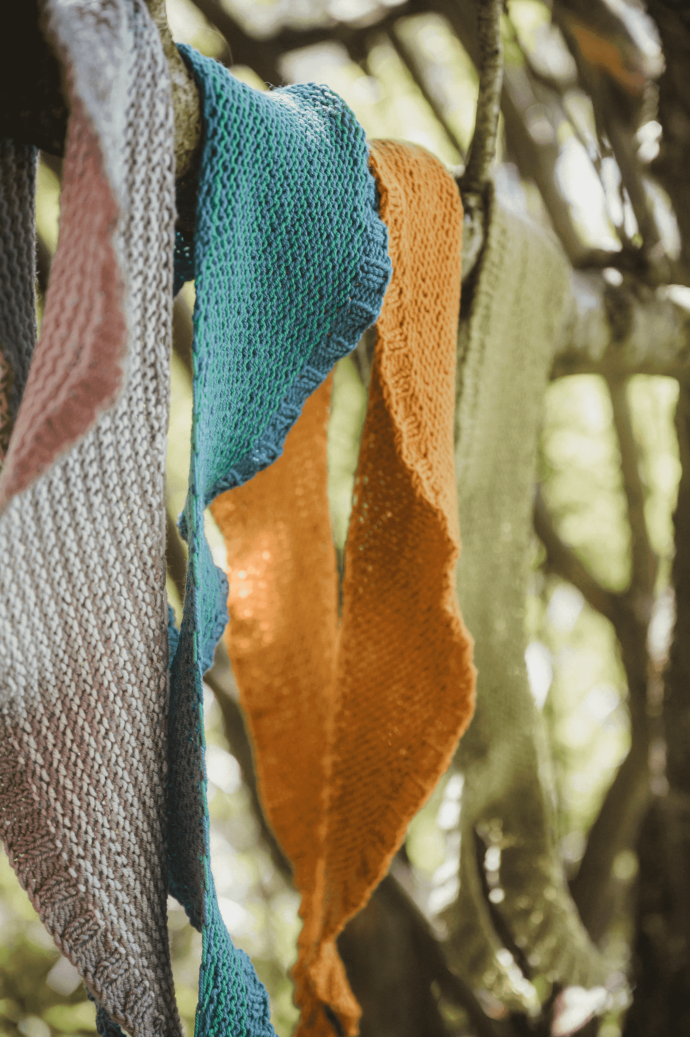 Nahaufnahme der gestrickten Schaltücher in Mondsichelform, in verschiedenen Farben aus Finkhof Wolle
