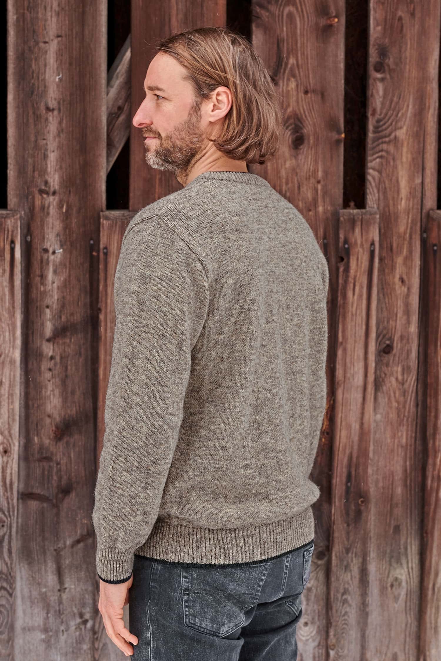 Rückansicht von Mann mit braunem Finkhof Pulli aus bio Wolle (kbT)