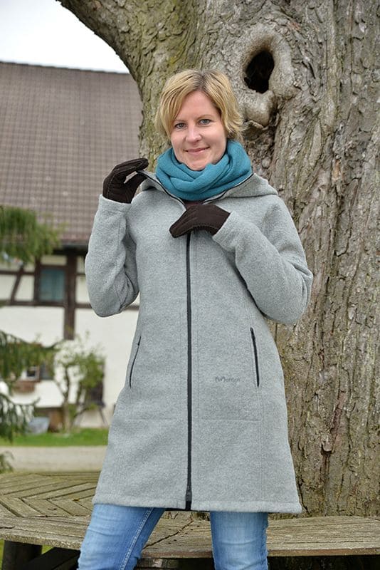 Frau mit grauem Mantel und türkisem Schal trägt dunkelbraune Fell-Fingerhandschuhe aus Pelzvelour