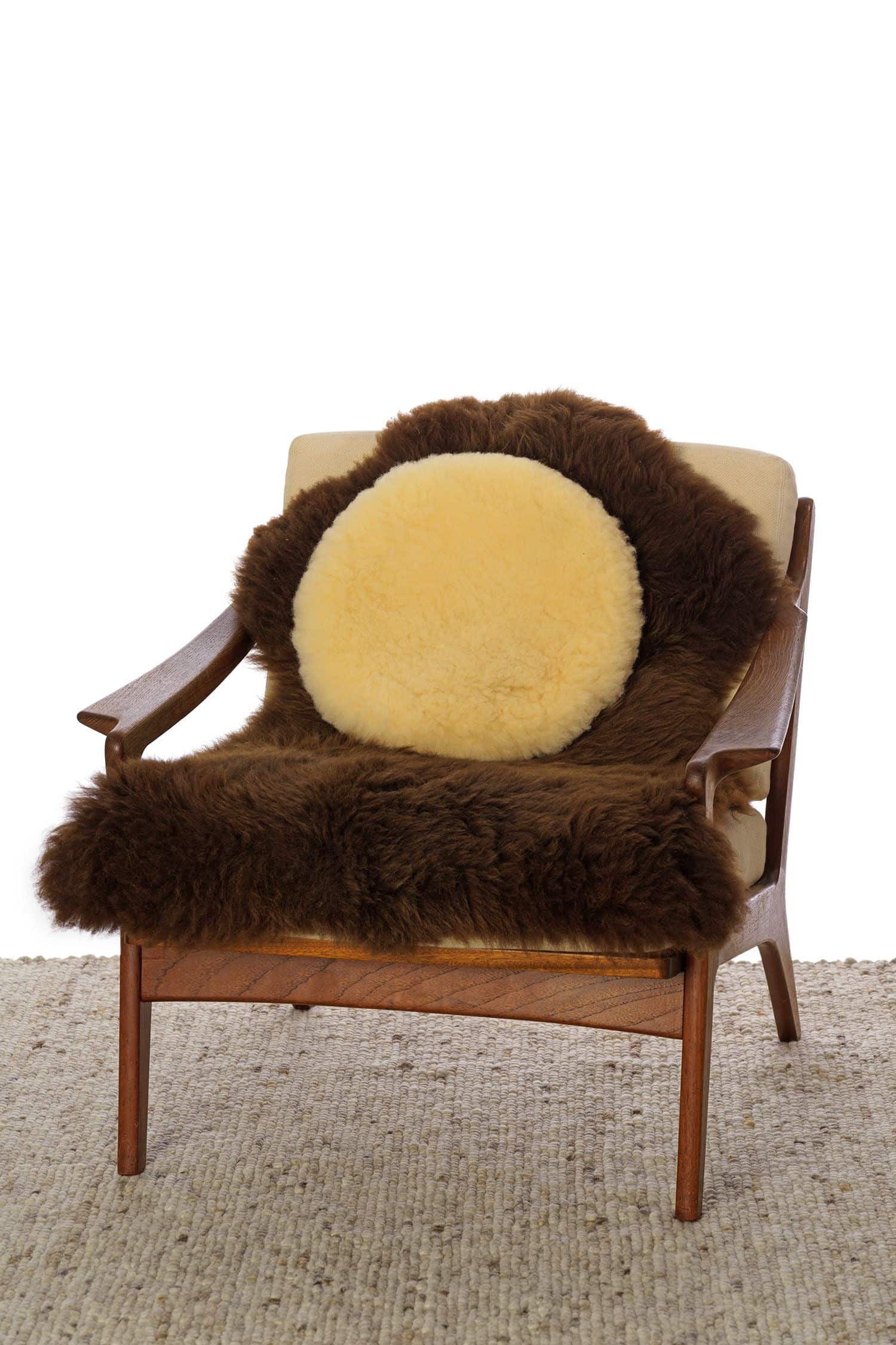 rundes relugan gegerbtes Wohlfühlkissen aus Finkhof Schaffell auf braunem Fell und Sessel