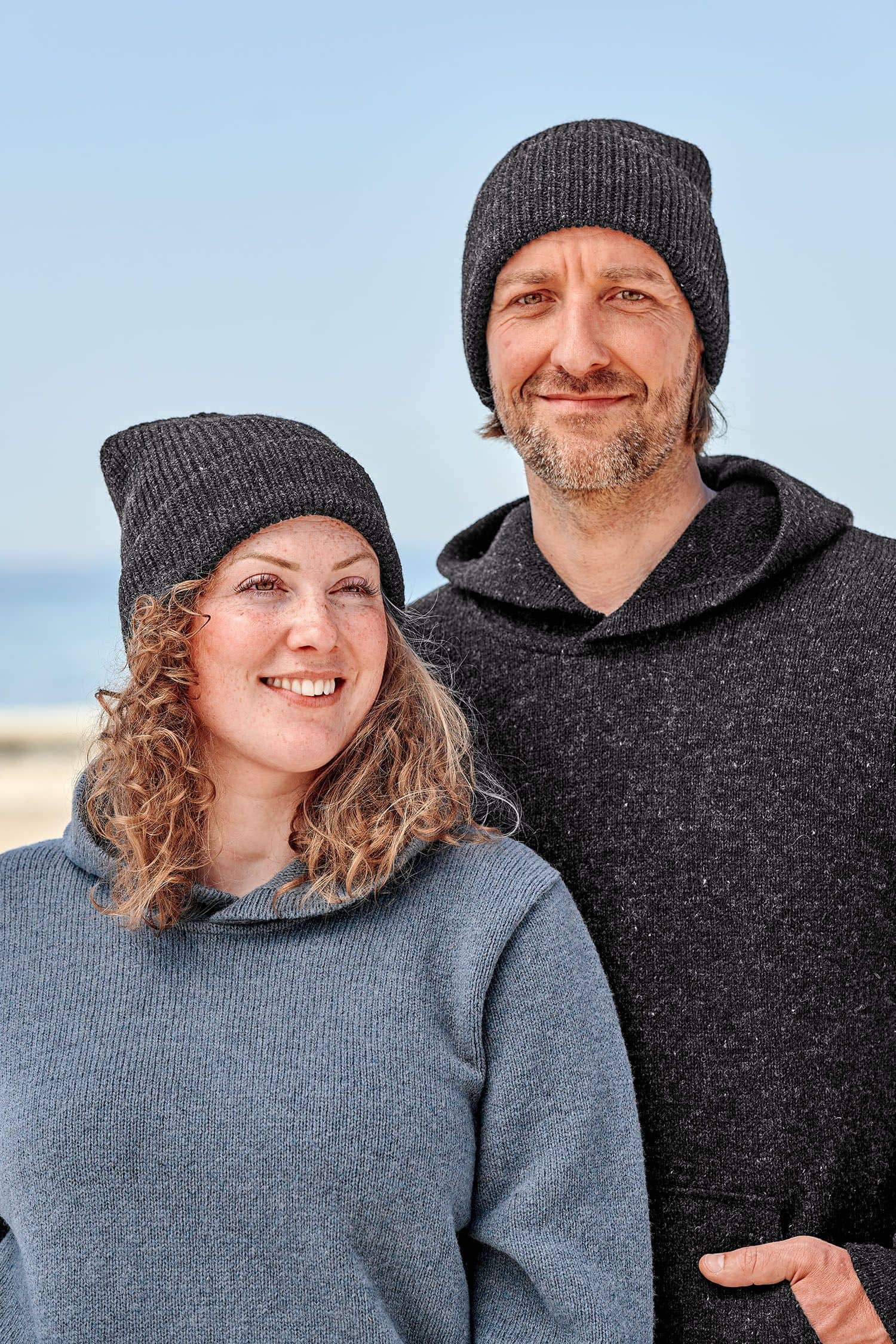 Finkhof-Mütze anthrazit Mann und Frau tragen Kapuzepullis und anthrazitgraue Finkhof Mützen aus bio Wolle (kbT)