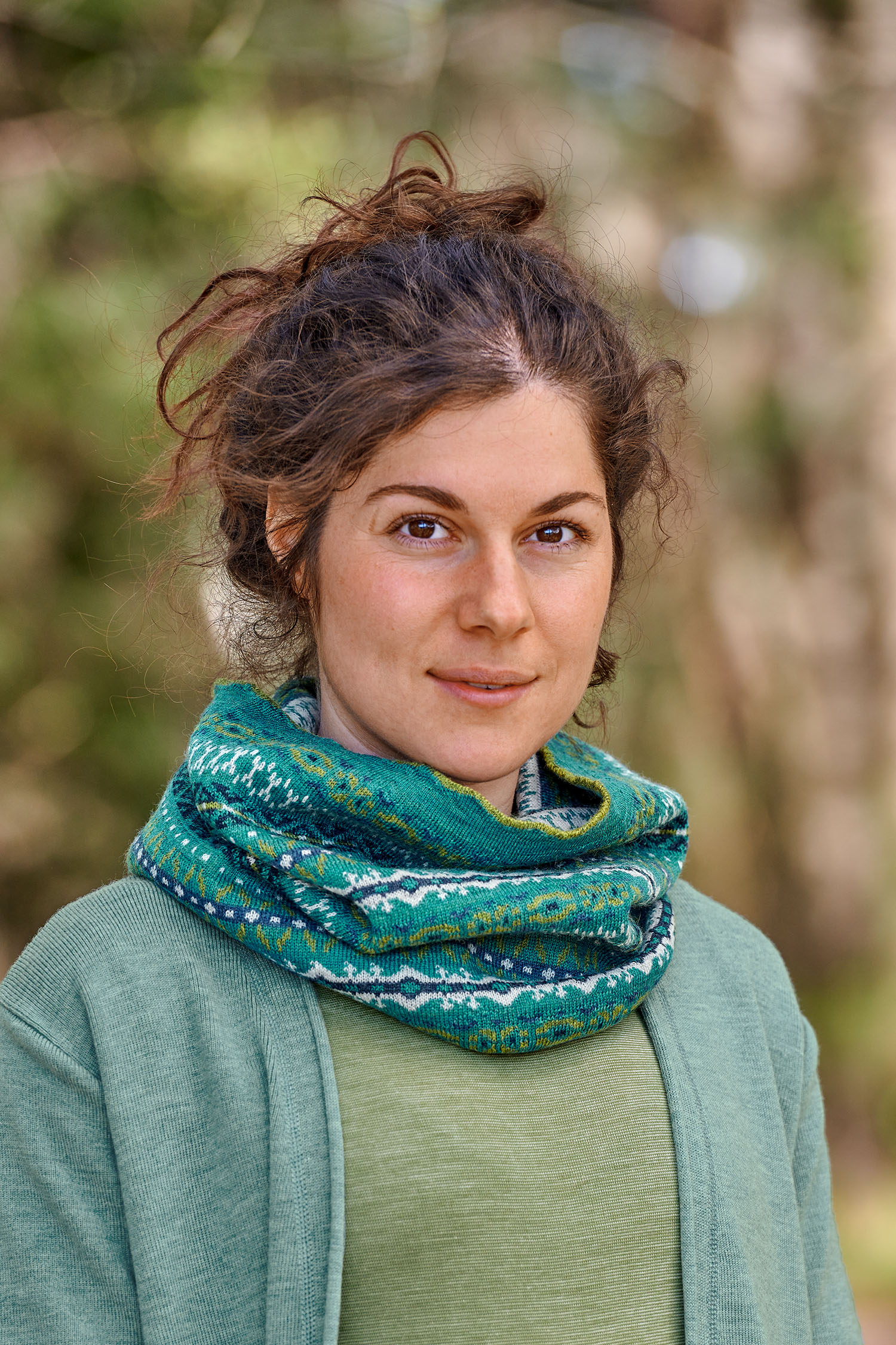 Loop Nordic aus reiner Bio-Schurwolle Frau mit grünem Shirt und blauem Cardigan trägt türkisen Loopschal mit nordischem Muster aus bio Wolle (kbT)